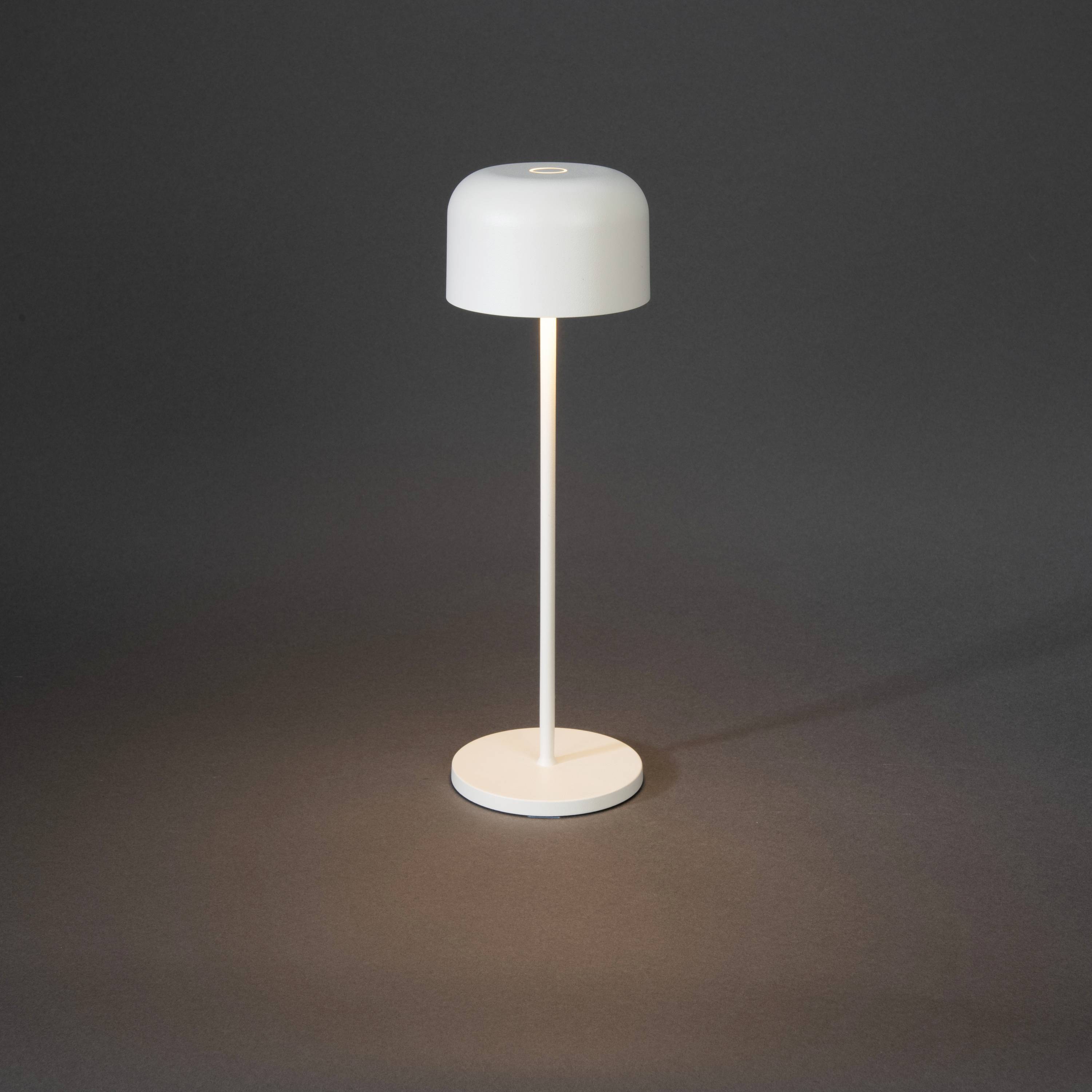Een moderne, vrij rechtopstaande, witte vloerlamp schijnt zacht op een donkere achtergrond.