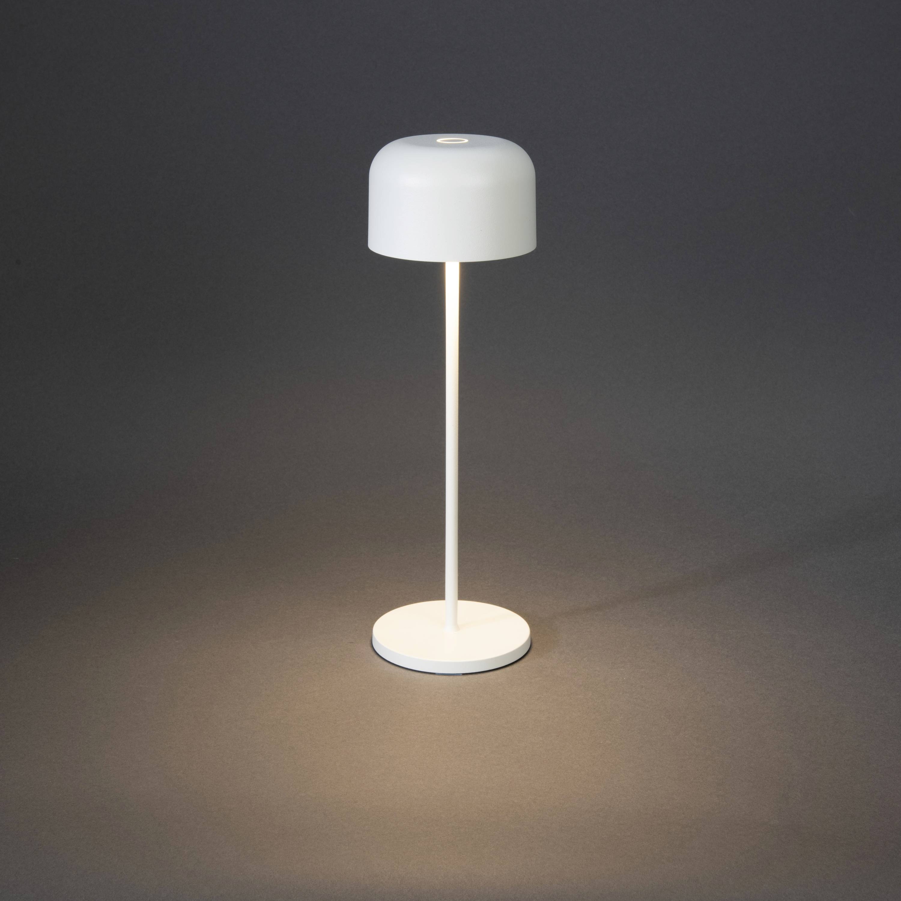 Een moderne, witte staande lamp met een ronde kap en een slanke voet, werpt helder licht op de grijze vloer.