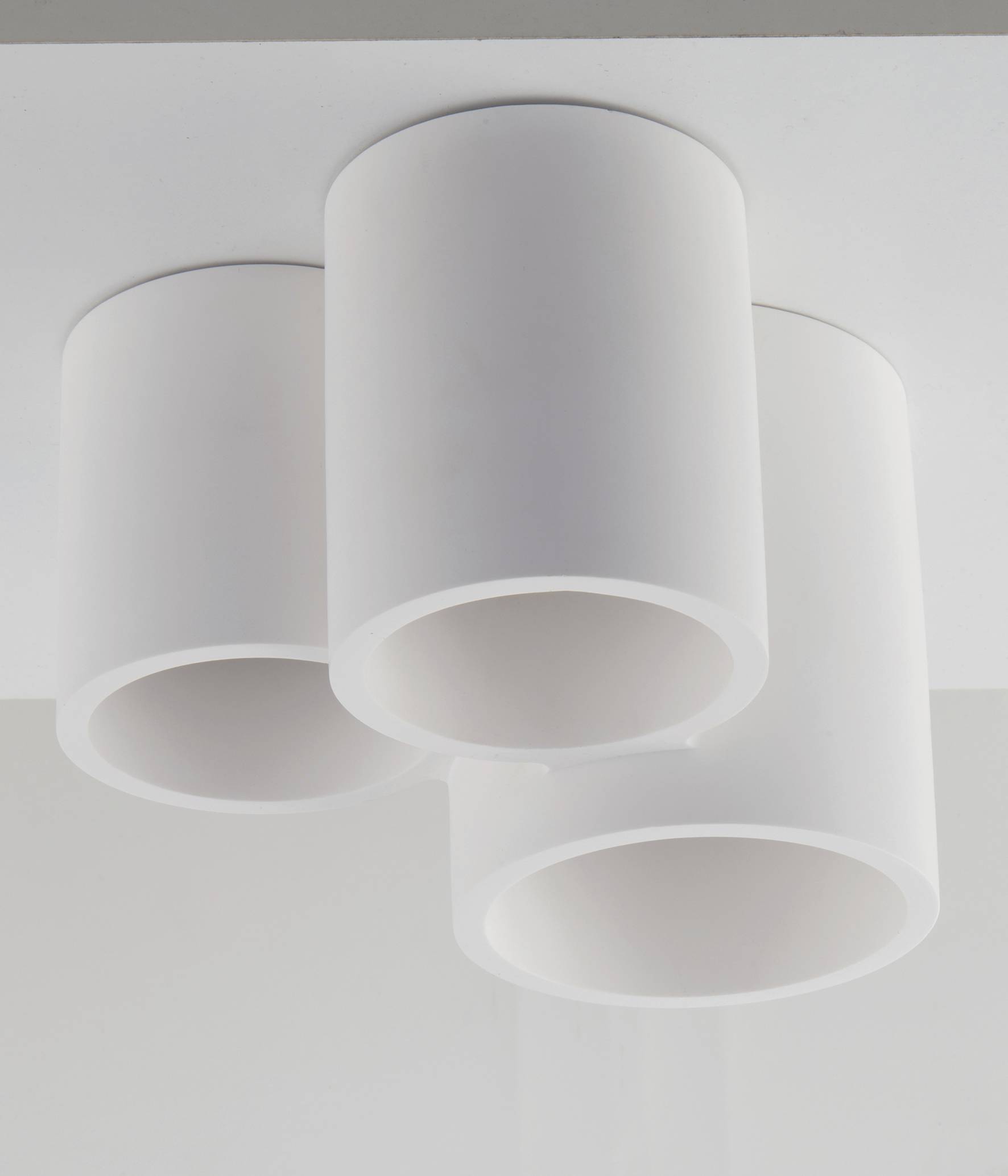 Drie cilindrische, witte plafondlampen die naast elkaar zijn geplaatst en zijn gemonteerd aan een wit plafond.