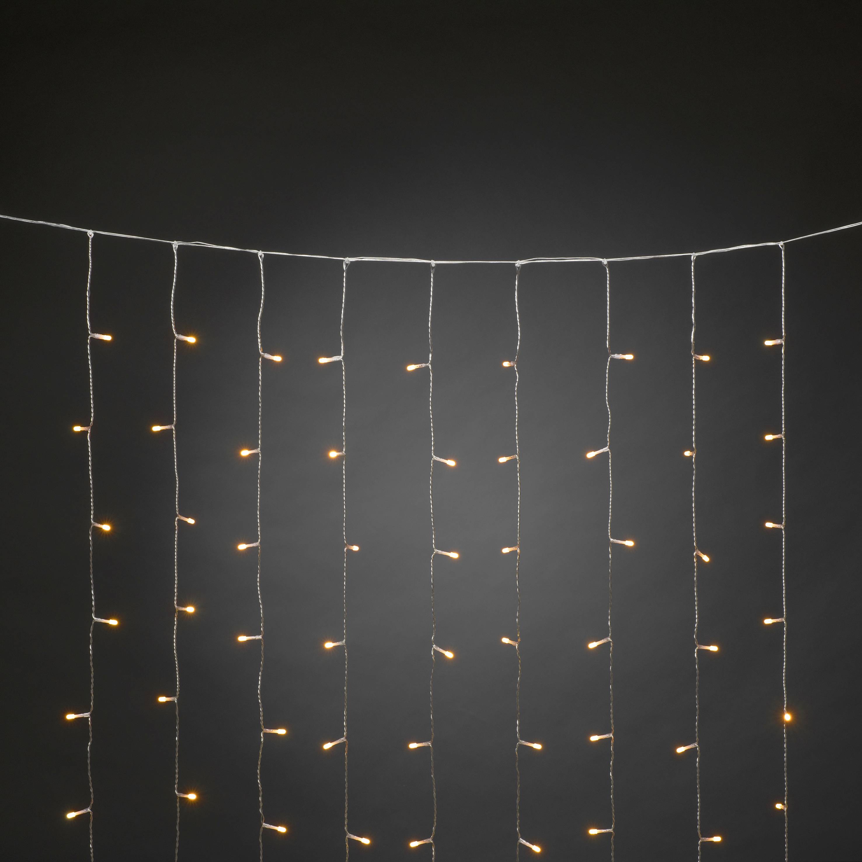 Lichtsnoer met warmwitte verlichting hangt voor een donkere achtergrond.