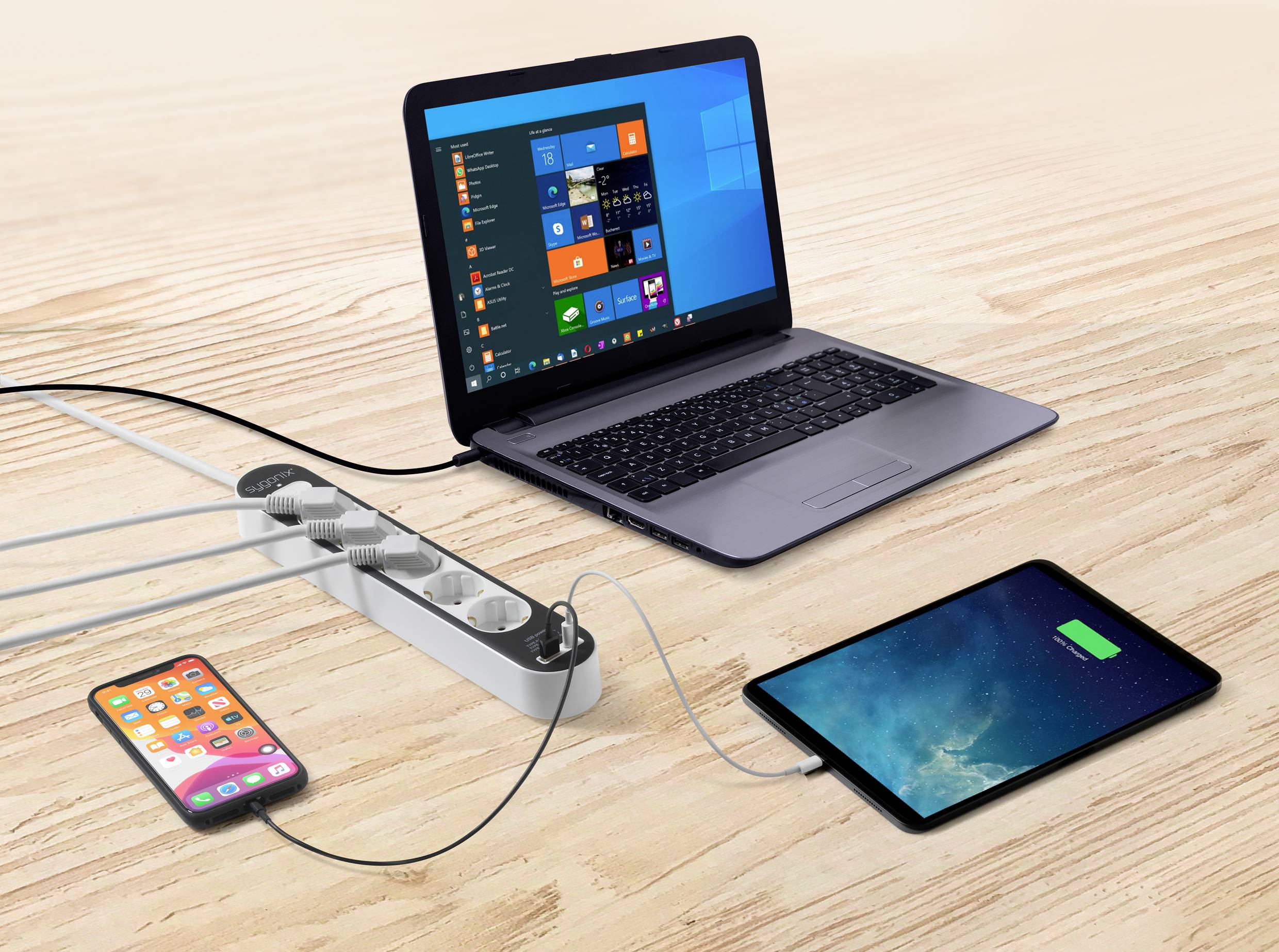 Een laptop, een tablet en een smartphone zijn allemaal aangesloten en worden gelijktijdig opgeladen via een stekkerdoos.