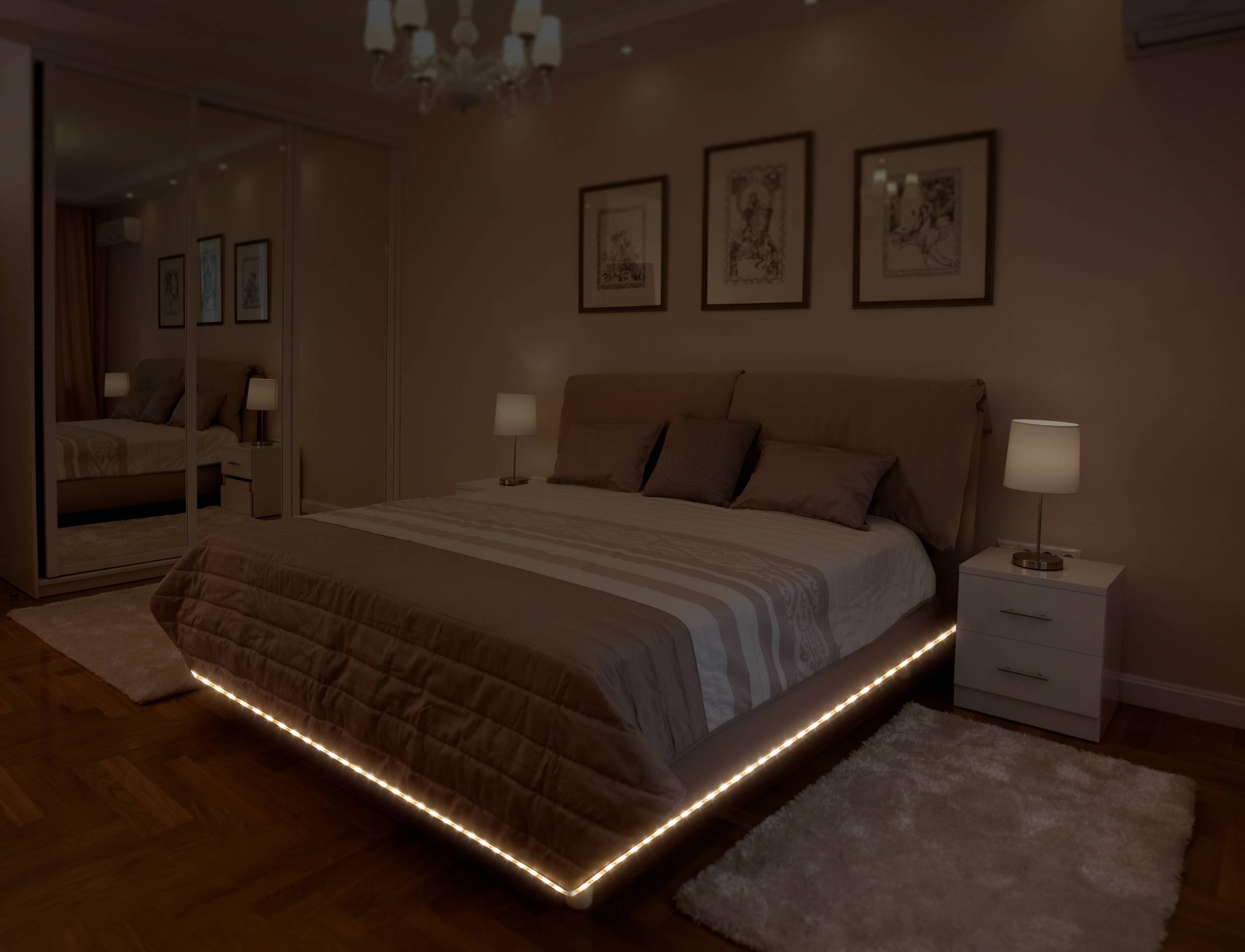 Een modern slaapkamer met een groot bed, omgeven door verlichte plinten, twee nachtkastjes met lampen en afbeeldingen aan de muur.