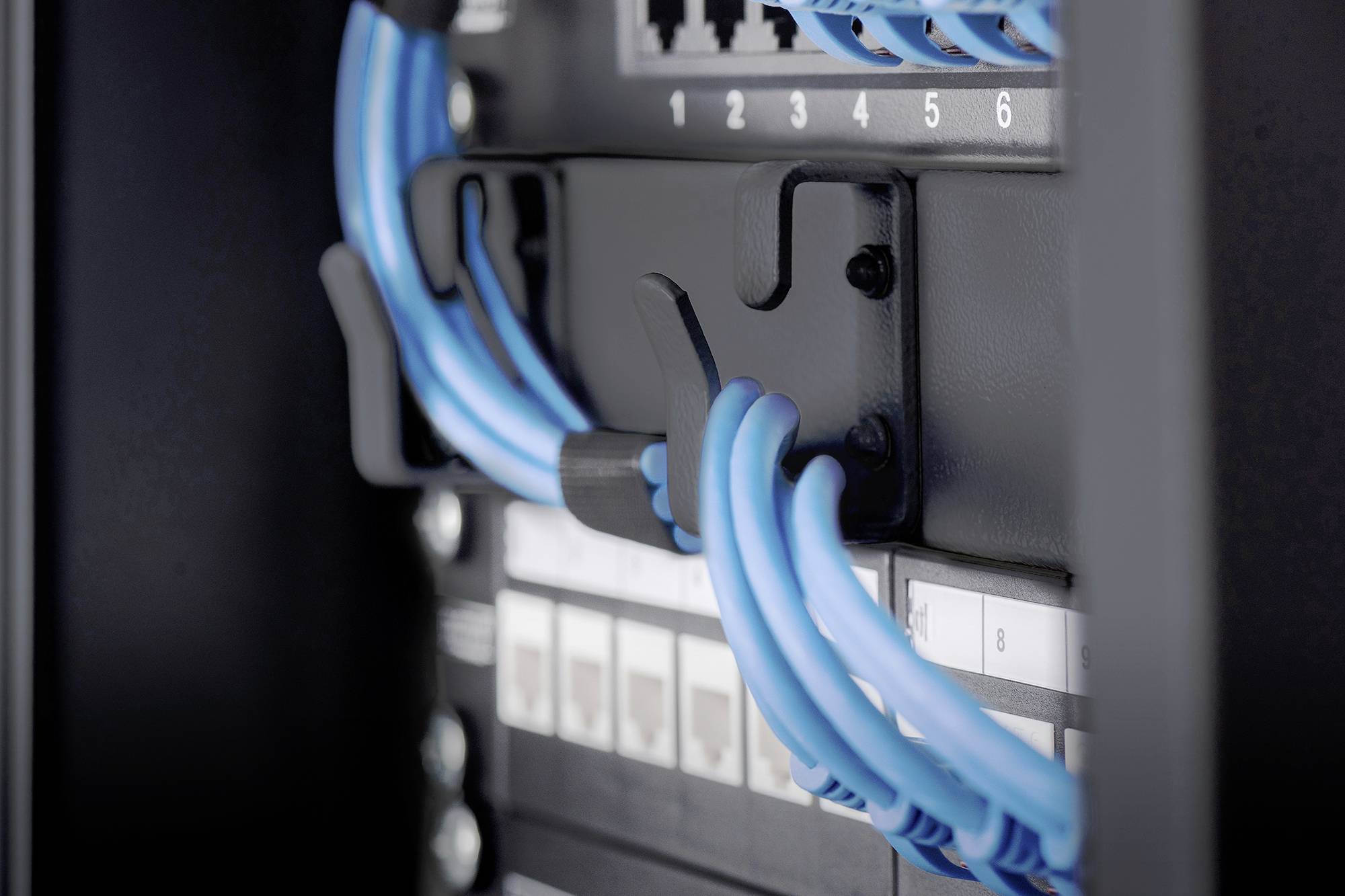 Blauw Ethernet-kabelbundel in een serverrek, aangesloten op netwerkaansluitingen voor gegevensoverdracht in een datacenter.