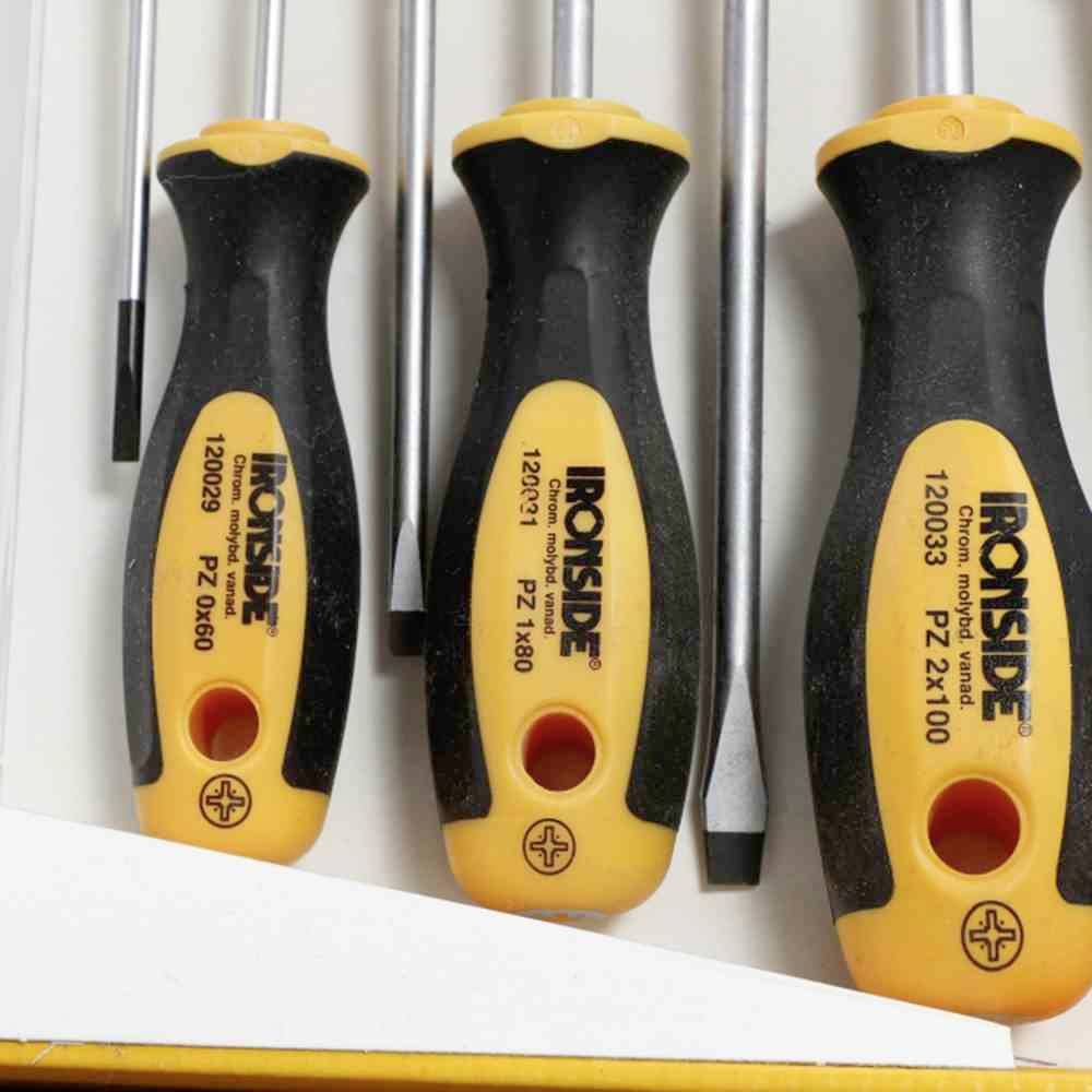 Vier schroevendraaiers met een zwart en geel handvat, elk van een verschillende grootte, liggen naast elkaar.