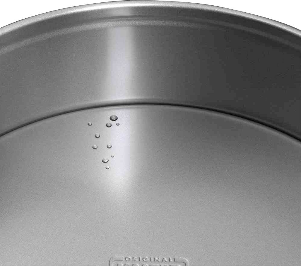 Waterdruppels op het metallische oppervlak van een pannendeksel, die de waterafstotende laag benadrukken.