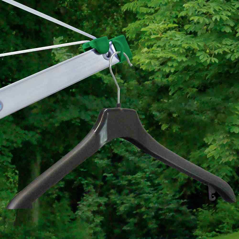 Een zwarte kleerhanger hangt buiten aan een waslijn voor een achtergrond van groen gebladerte.