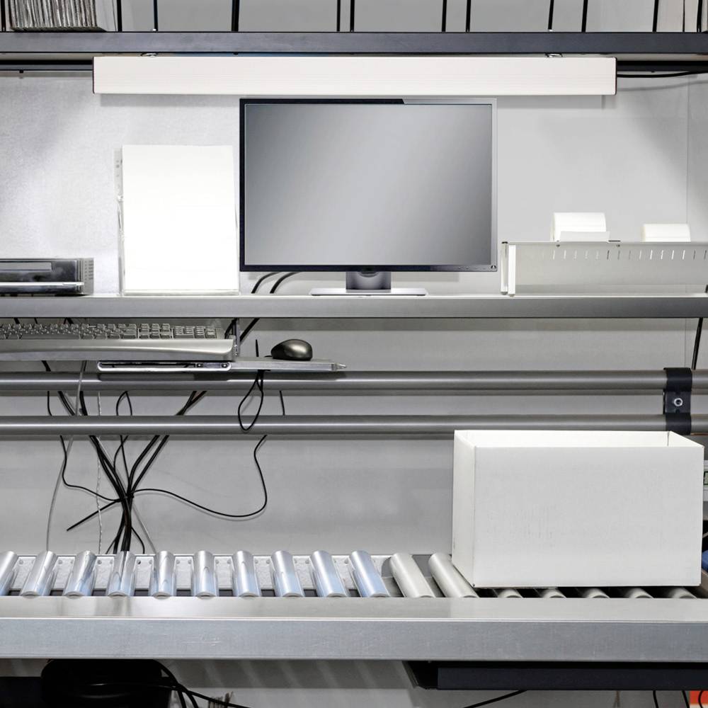 Productielijnen met computerbeeldscherm, toetsenbord en verpakkingsdoos op transportband. Technische uitrusting op de achtergrond.