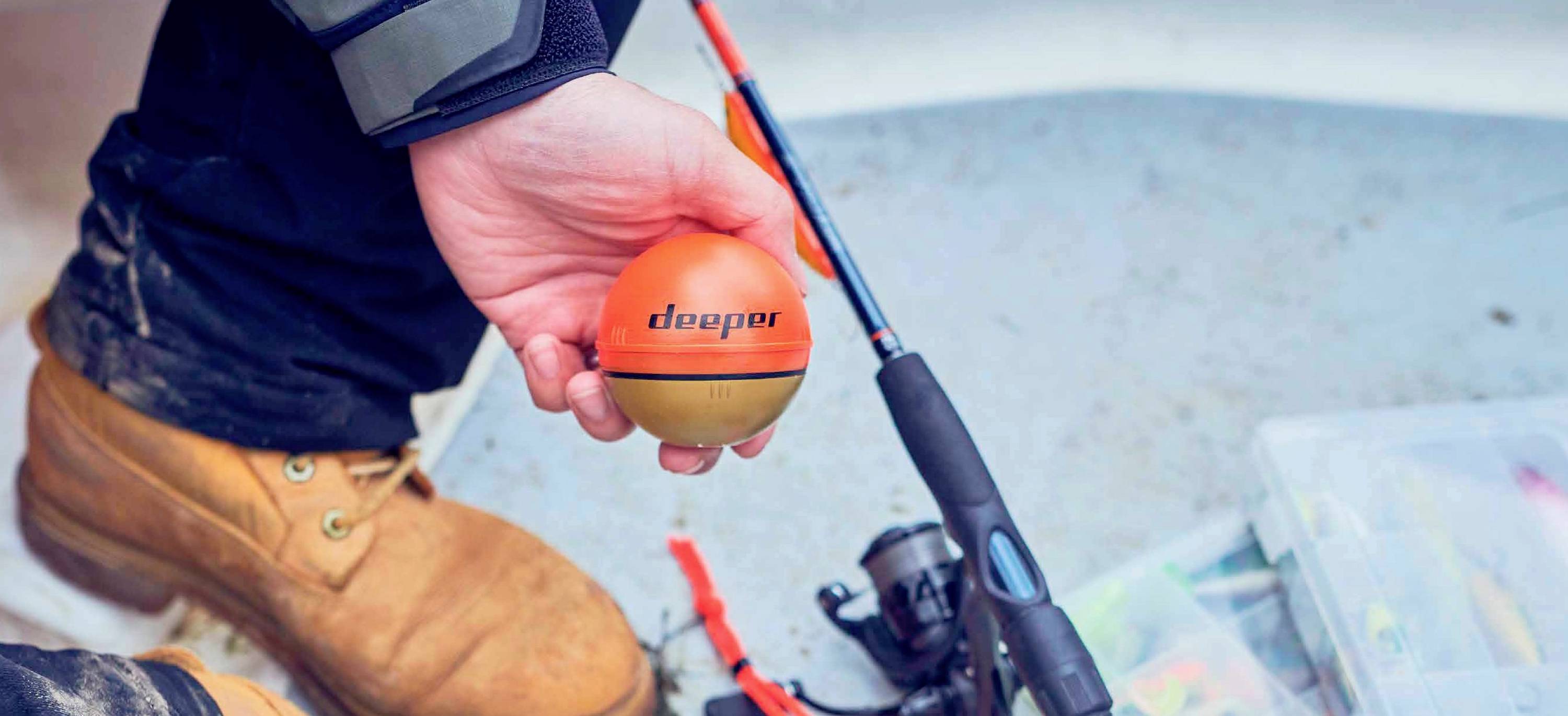 Een persoon houdt een oranje zwemboei vast, naast een visuitrusting-opbergdoos en een hengel op de vloer van een boot.