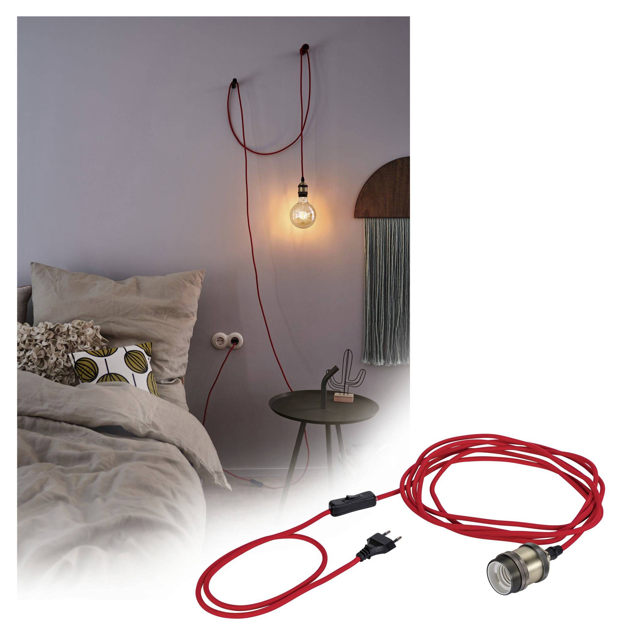 Een rode hanglamp met een lampfitting, hangt verlicht naast een bed met een tafel.