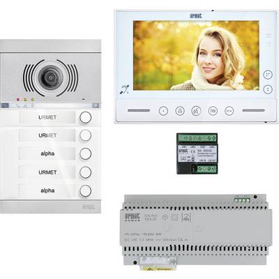 Intercom met buiten- en binnenmodule. Het binnenmodule toont een vrouw op een display. Twee URMET alpha naamplaatjes zijn zichtbaar.