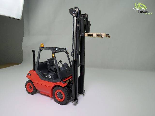 Een rode heftruck tilt een lege pallet op in de lucht. De achtergrond is grijs.