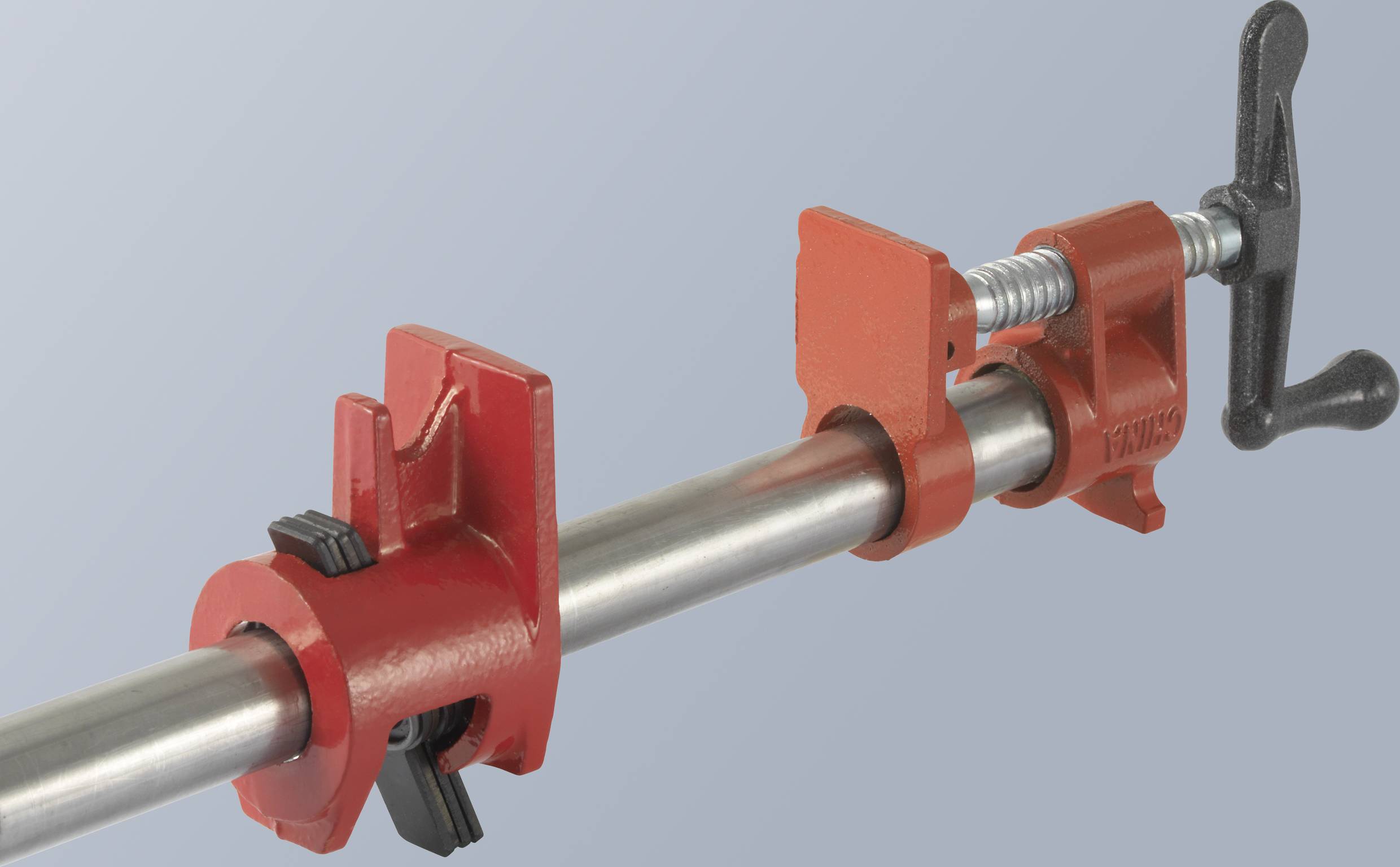 Een rood buisspangereedschap met schroefmechanisme voor een grijze achtergrond.