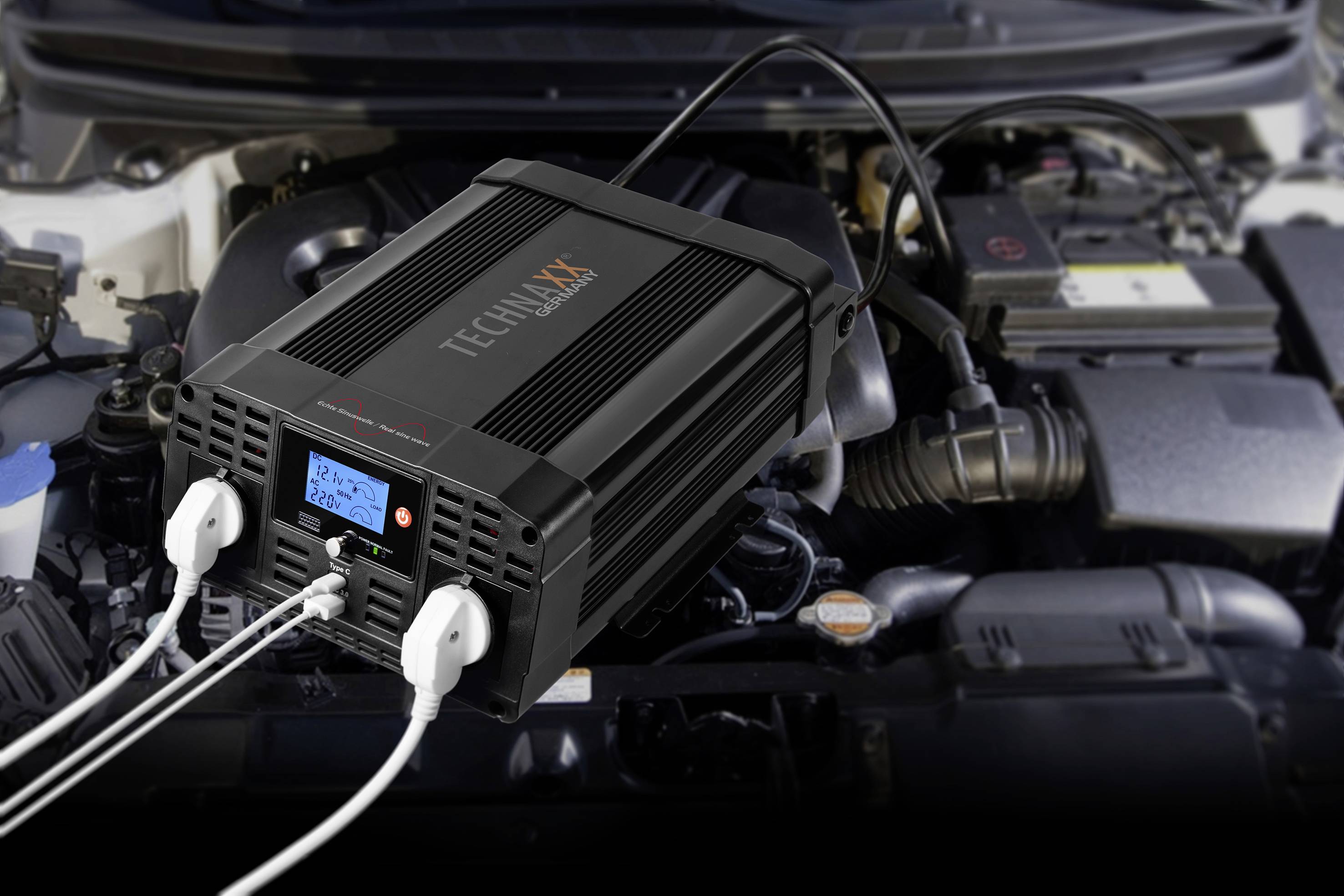 Autoinverter in de motorruimte, aangesloten op een autoaccu, zet gelijkstroom om in wisselstroom; voor mobiele stroomvoorziening.