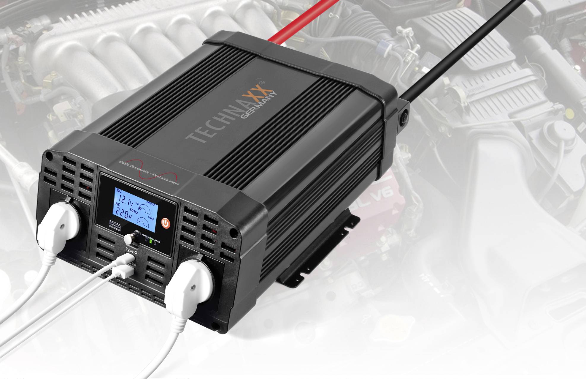 Een zwarte spanningsomvormer met twee stopcontacten en een display toont '12,7V 220V'. Op de achtergrond is een motorruimte zichtbaar.