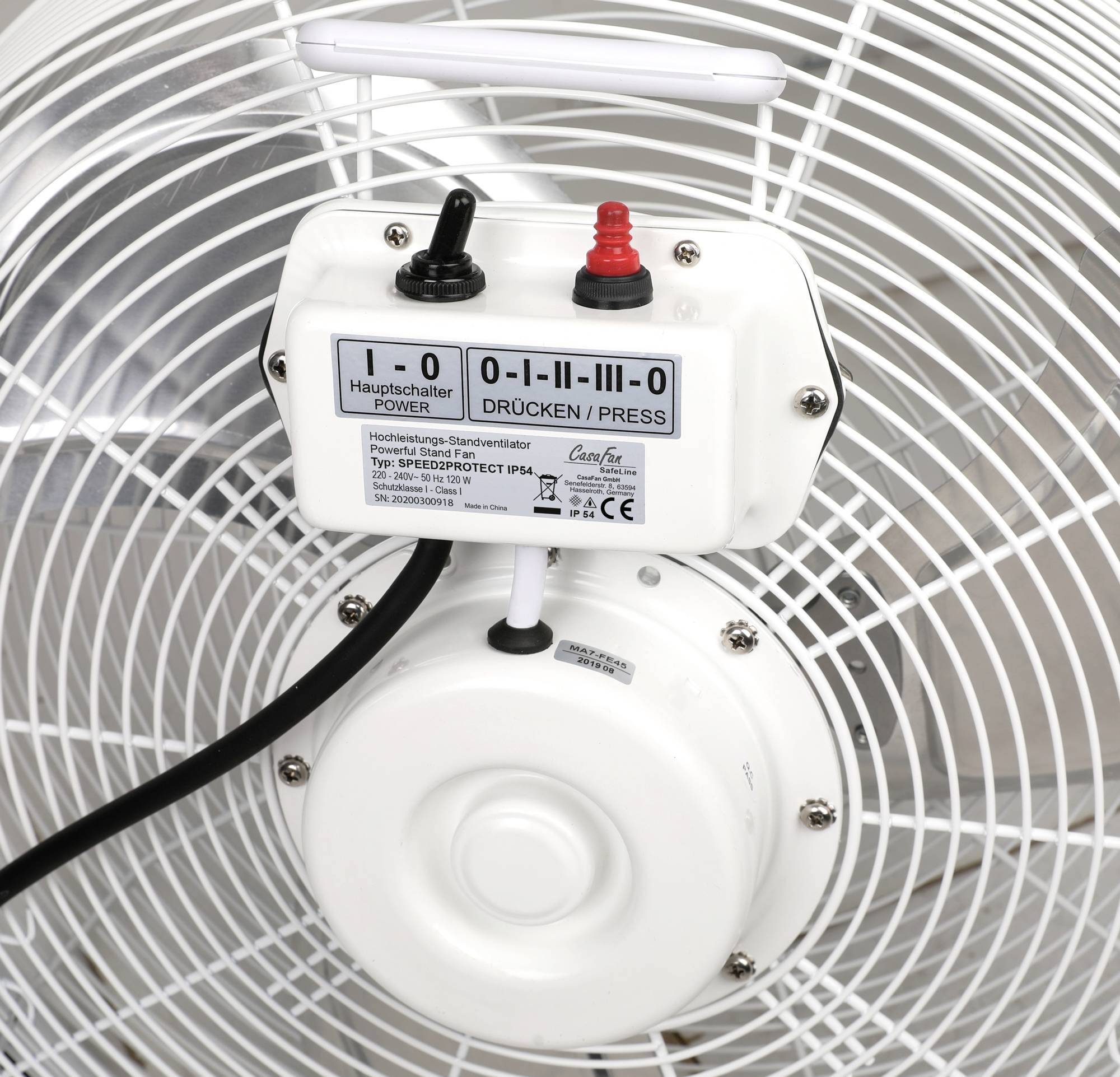Close-up van een ventilator. Het bedieningspaneel is zichtbaar met een schakelaar en het opschrift 'DRÜCKEN/PRESS'.