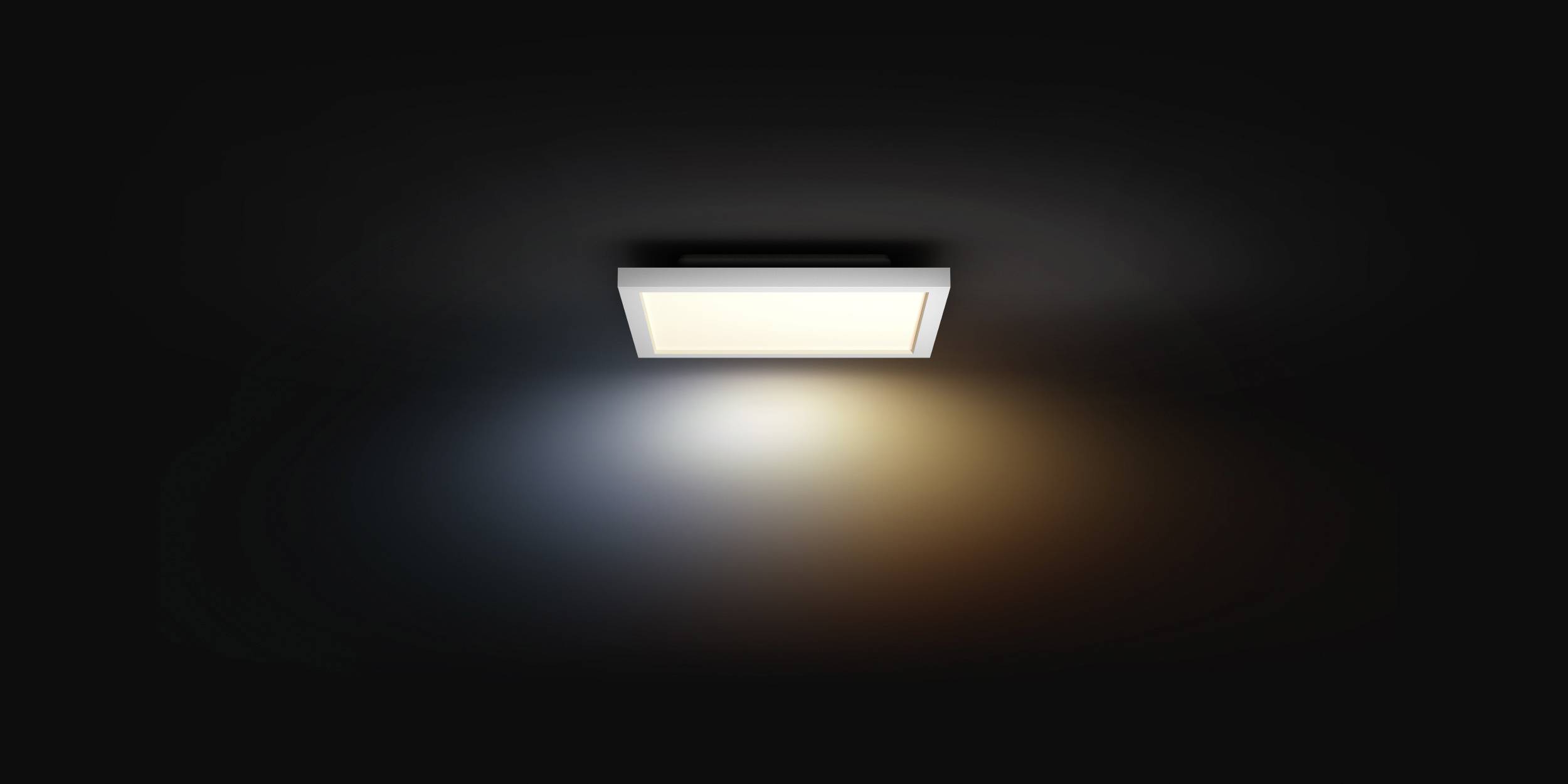 Een rechthoekige lamp schijnt aan het plafond. Links blauw licht, rechts warm geel licht. Donkere achtergrond.