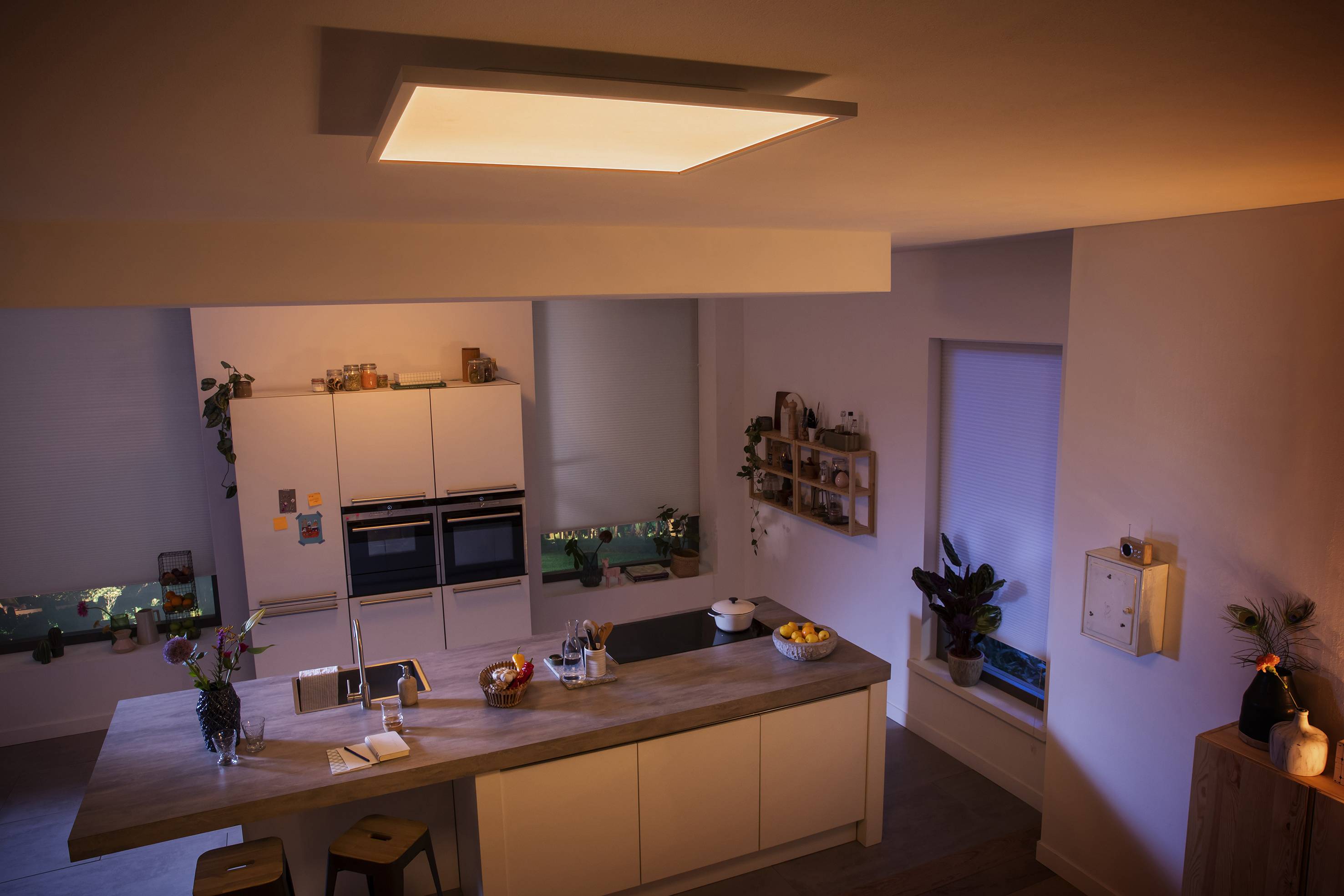 Een moderne keuken met een centrale eilandindeling, omgeven door witte kasten. Warme verlichting creëert een gezellige sfeer.