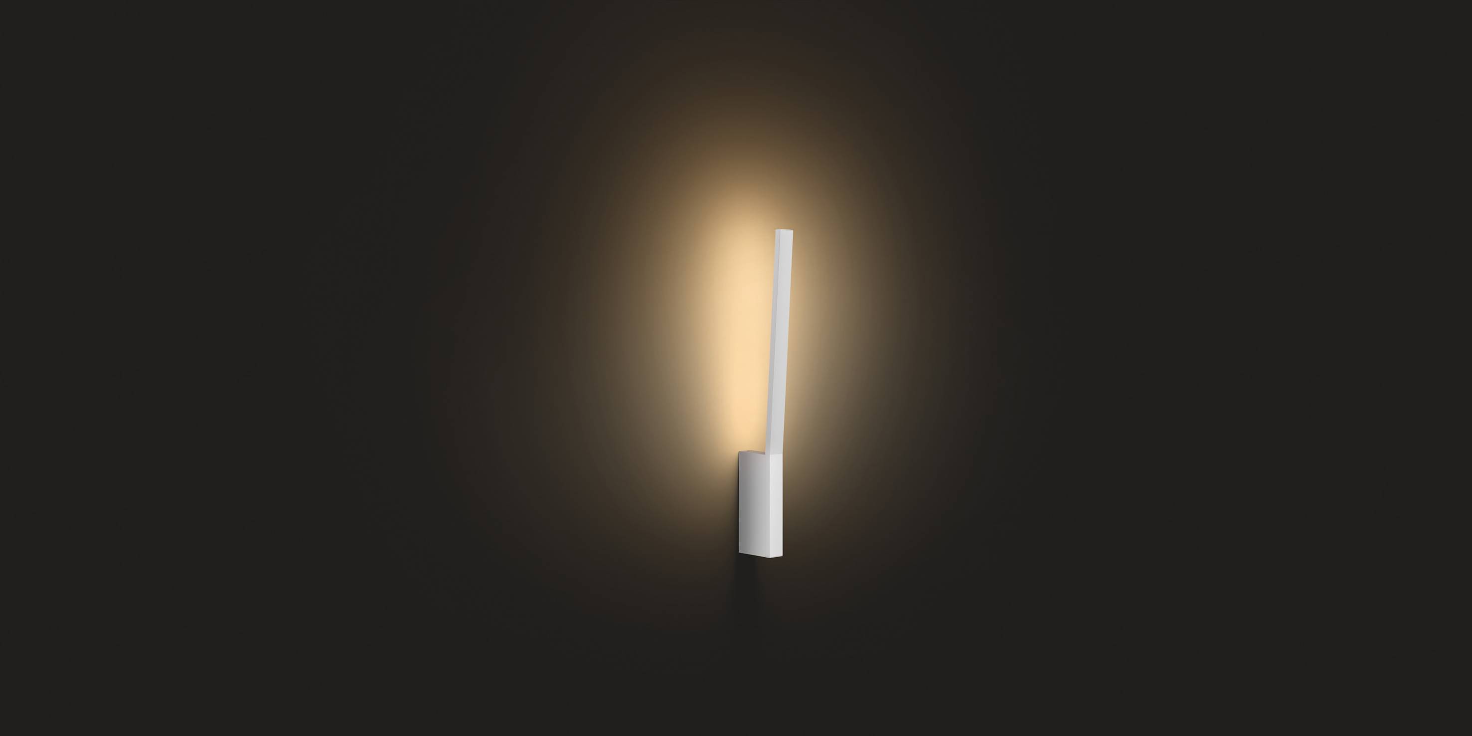 Een slanke, minimalistische wandlamp werpt warm licht op een donkere achtergrond en creëert een rustige sfeer.