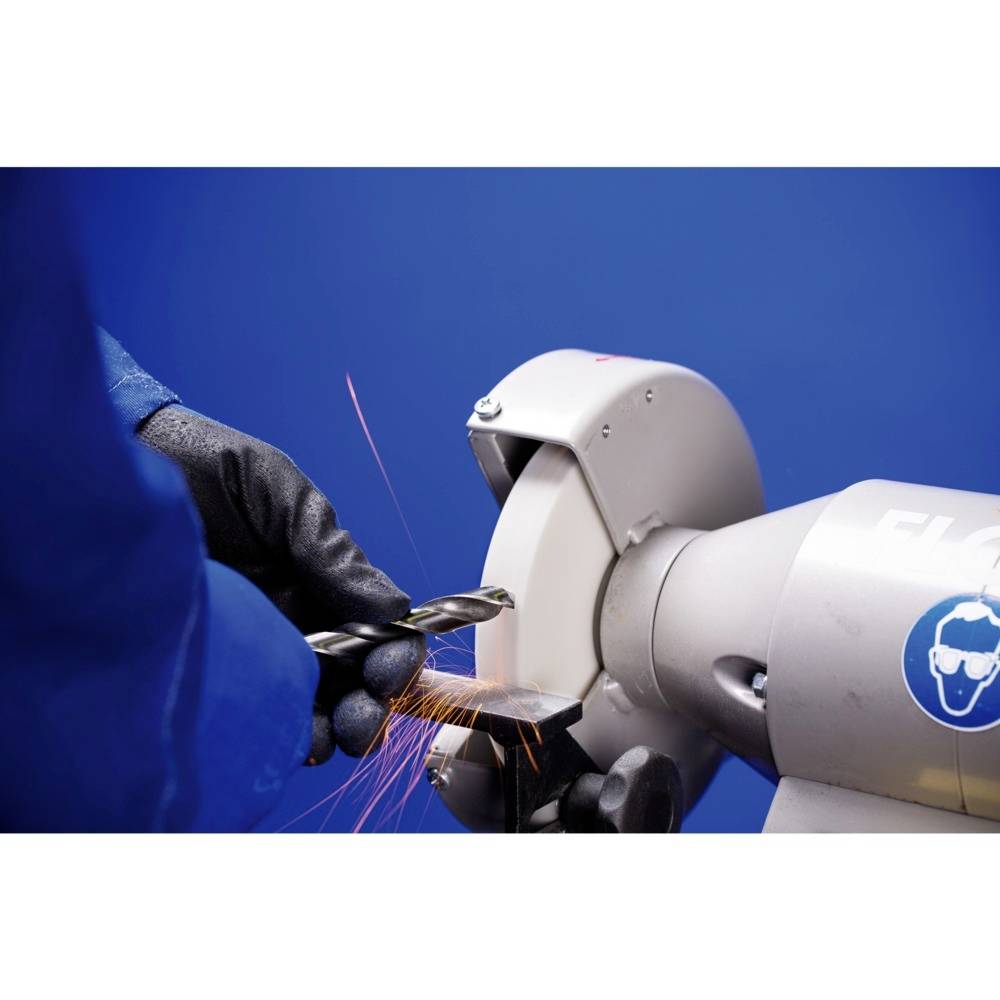 Een persoon in blauwe beschermende kleding slijpt een metalen stuk met een haakse slijper, vonken spatten rond, tegen een blauwe achtergrond.