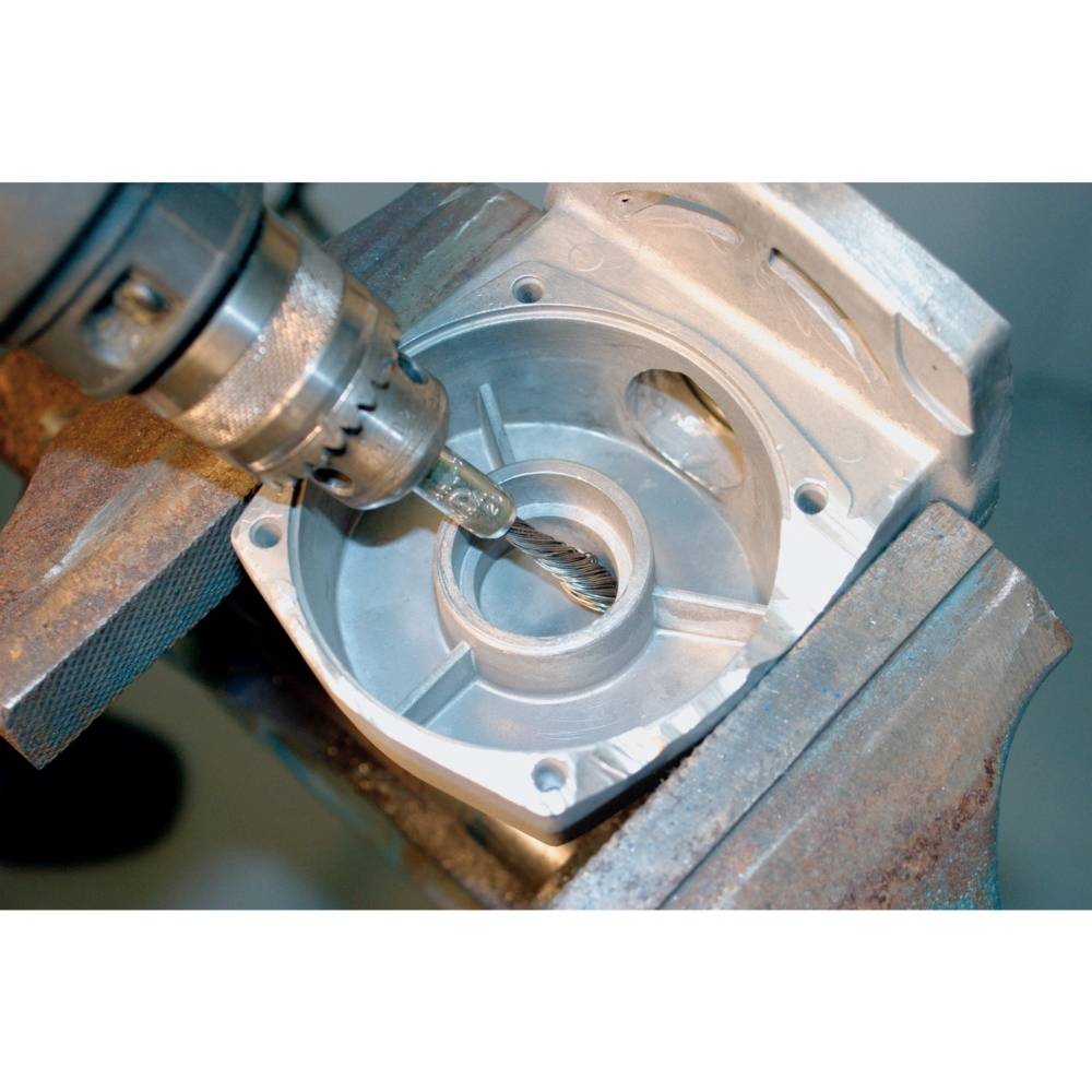 'Een metalen schaal wordt bewerkt door een boor die in een bankschroef is vastgeklemd. De focus ligt op precisiewerk.'