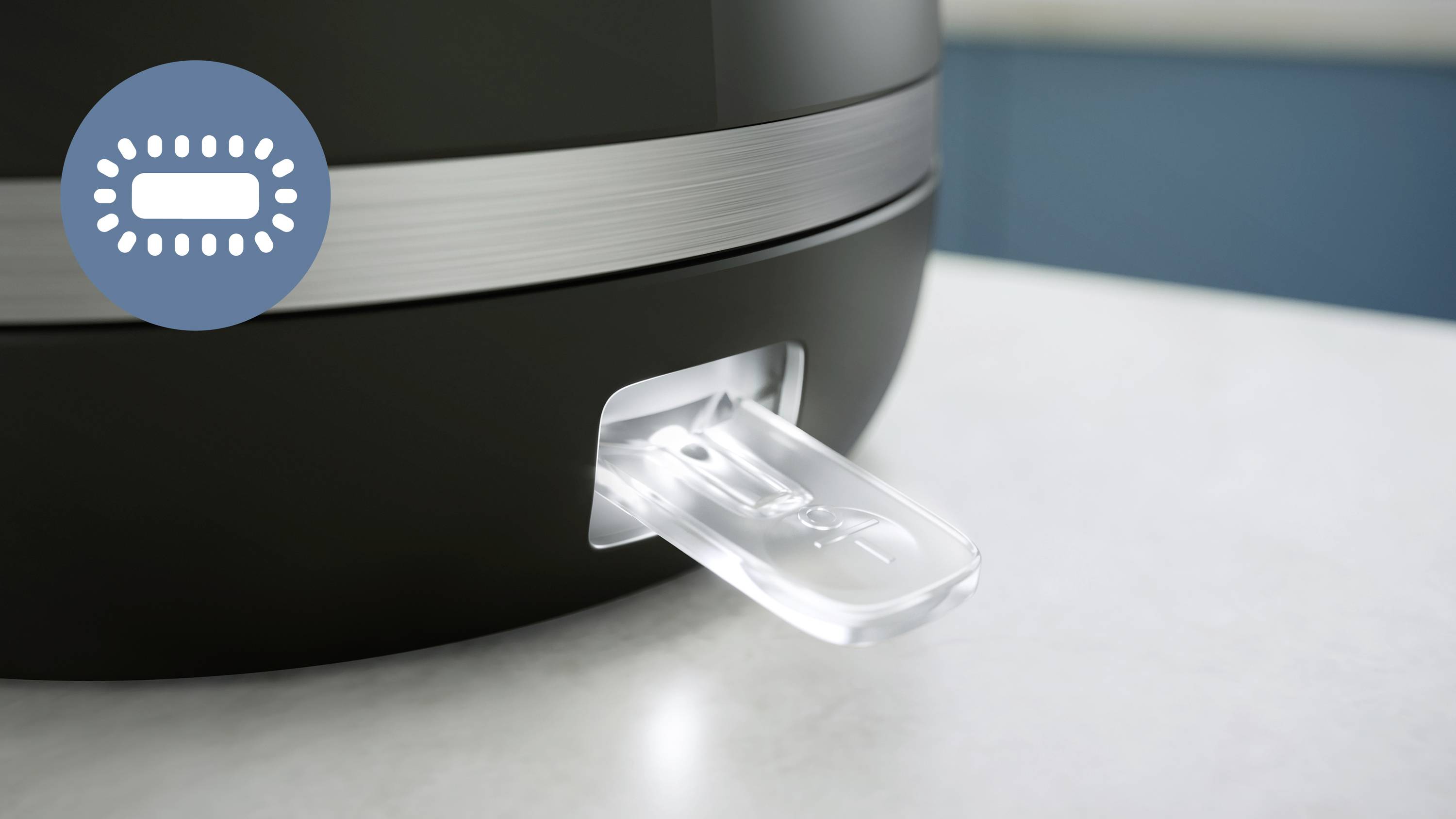 Een fragment van een zwart apparaat met een transparante plastic hendel aan de onderkant. Ernaast een symbool van een pil in een cirkel.