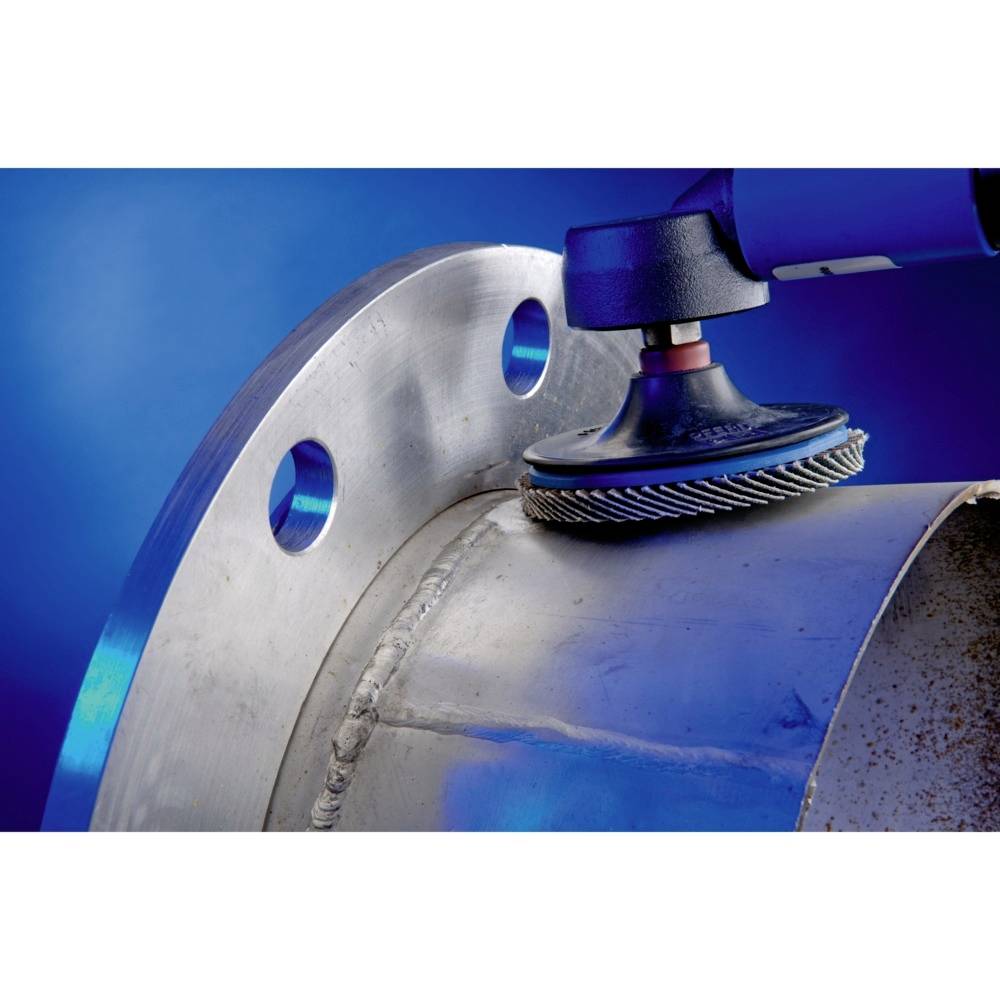 Een metaalschuurapparaat bewerkt een cilindrisch metalen oppervlak met ronde gaten, tegen een blauwe achtergrond.