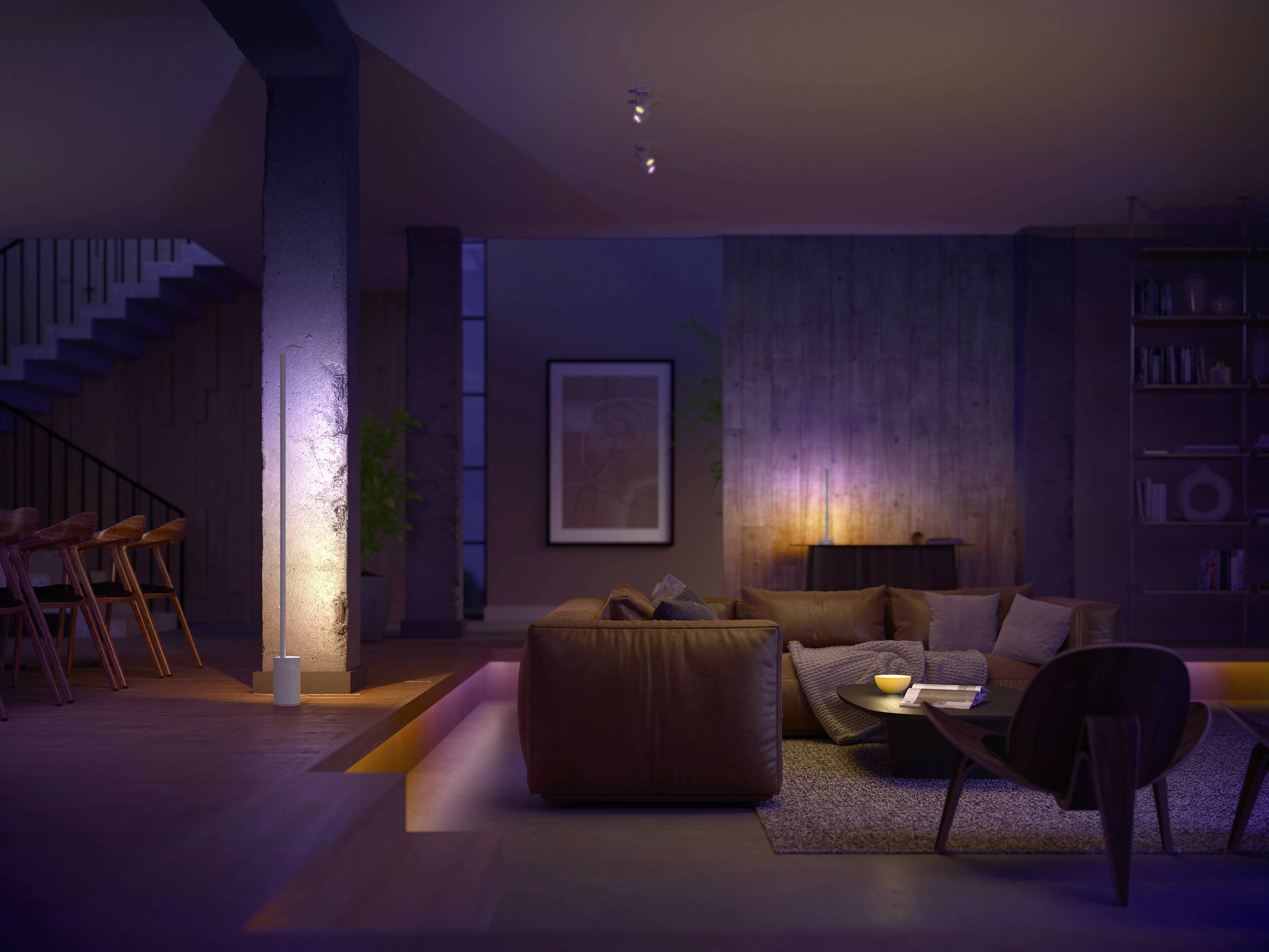 Een woonkamer met moderne verlichting. Een bruine leren bank, een ronde salontafel en een rek op de achtergrond. Gedimde, warme verlichting.