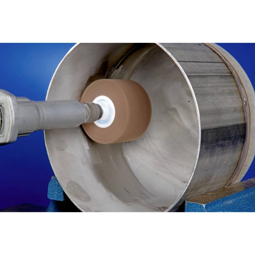 Industriële slijpmachine bewerkt de binnenkant van een grote metalen buis. De slijpschijf verwijdert materiaal voor oppervlaktebewerking.