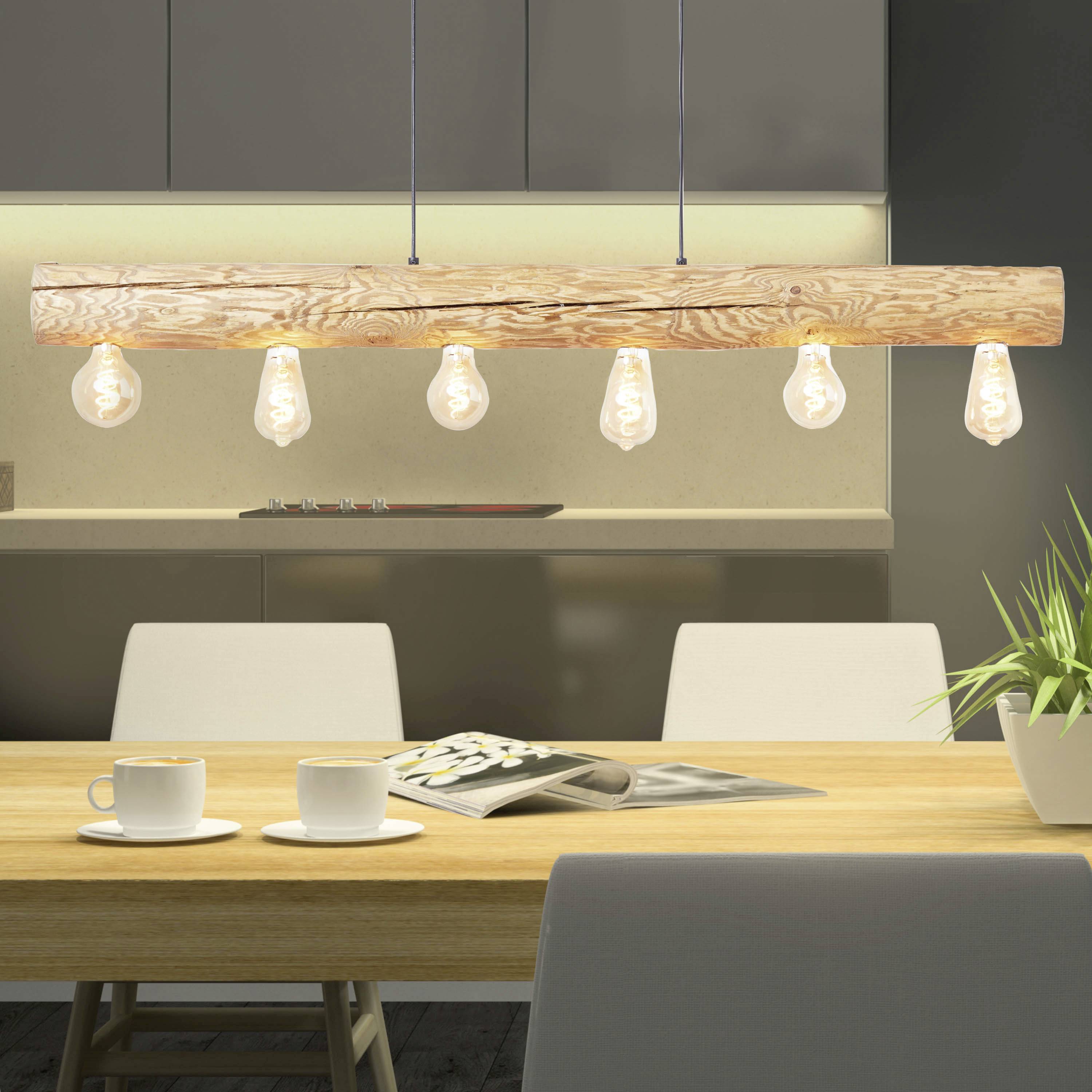 Een houten tafel met een krant erop en een plant ernaast. Aan het plafond hangt een houten lamp met meerdere gloeilampen.