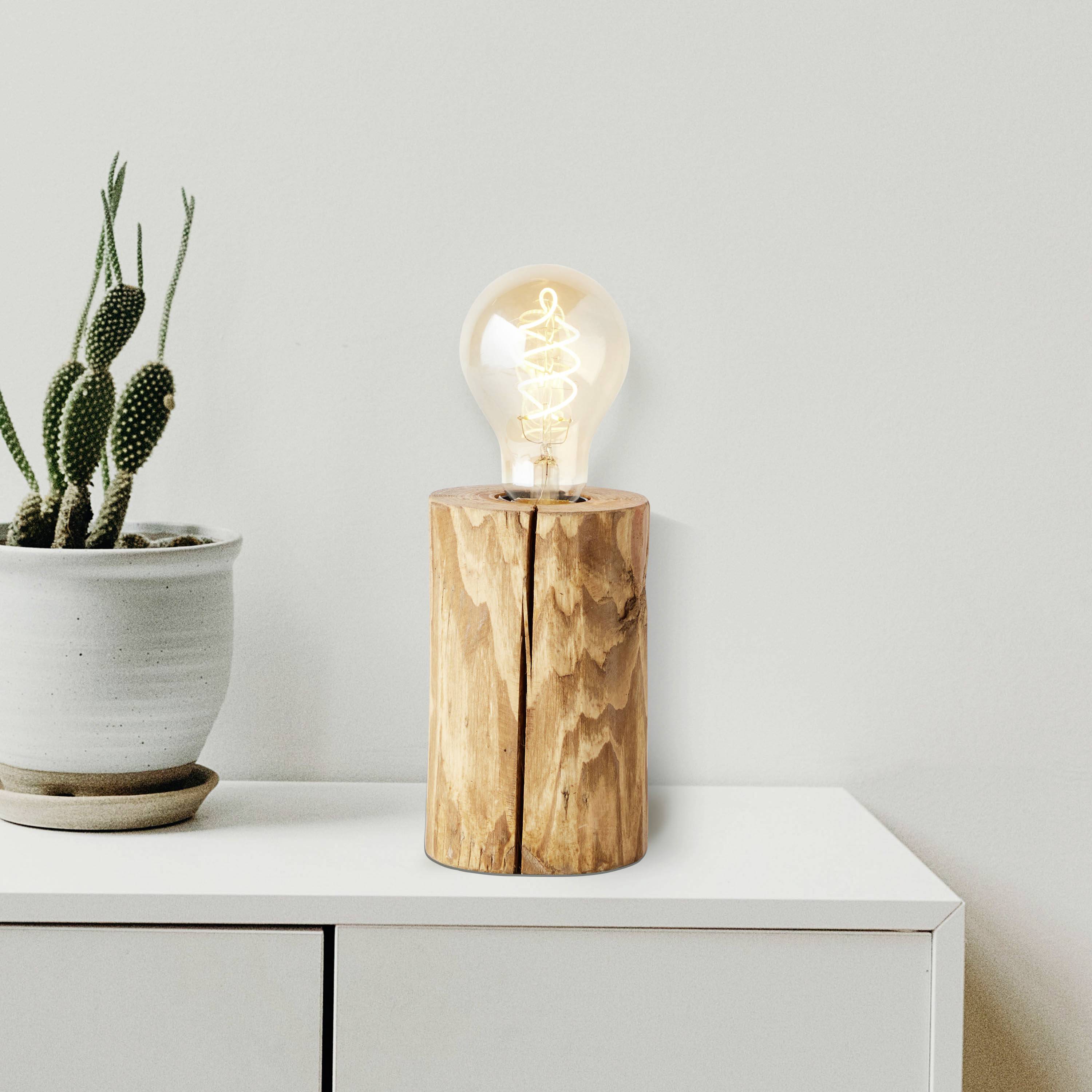 Houten tafel met een cactusplant in een pot en een houten lamp met gloeilamp. Eenvoudige, moderne decoratie in neutrale kleurtinten.