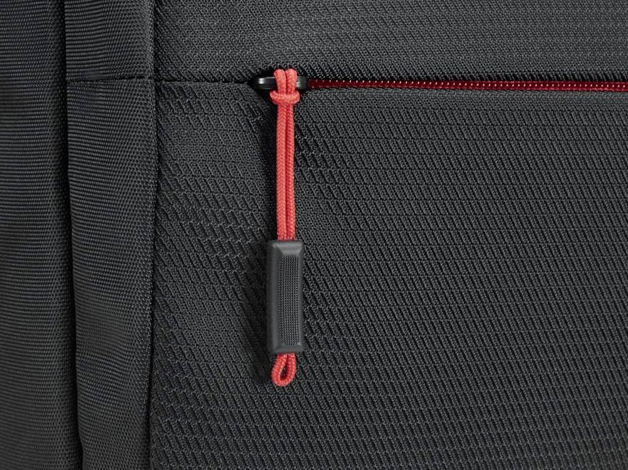 Close-up van een zwarte rugzak met een rode ritssluiting. De structuur van de stof is duidelijk zichtbaar.