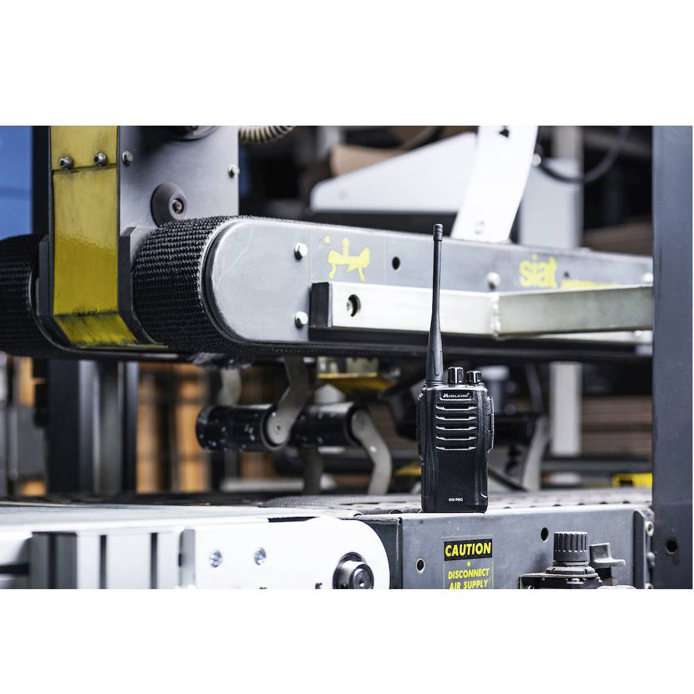 Een portofoon staat op een industrieel transportband in een fabriekromgeving, symboliseert communicatie en controle in het industriële proces.