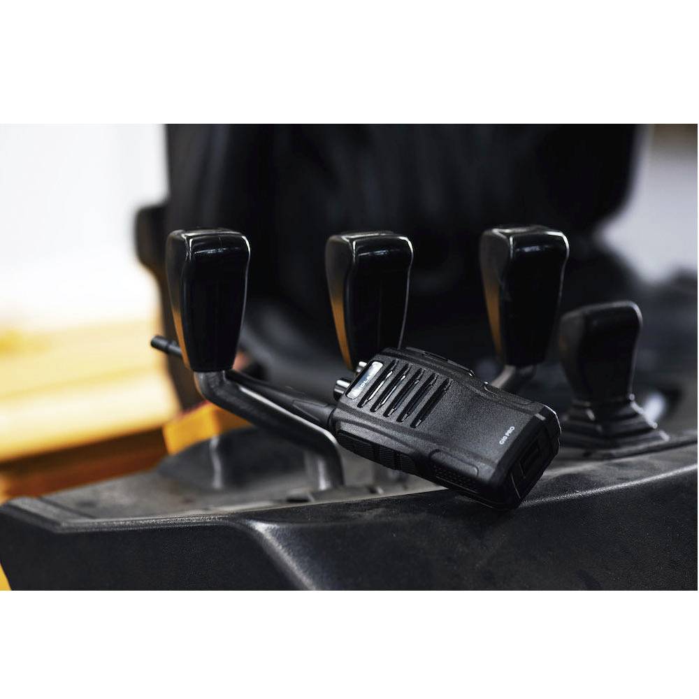 Een portofoon ligt op de stoel van een voertuig naast de versnellingspook. Het wijst op gebruik in een industriële omgeving.