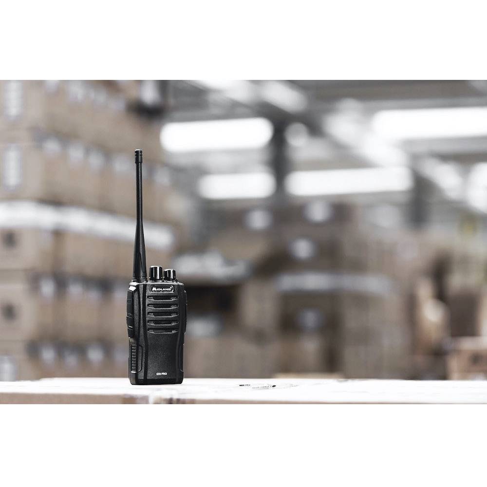 Een zwarte walkietalkie op een tafel in een magazijnomgeving. Op de achtergrond zijn onscherpe gestapelde dozen zichtbaar.