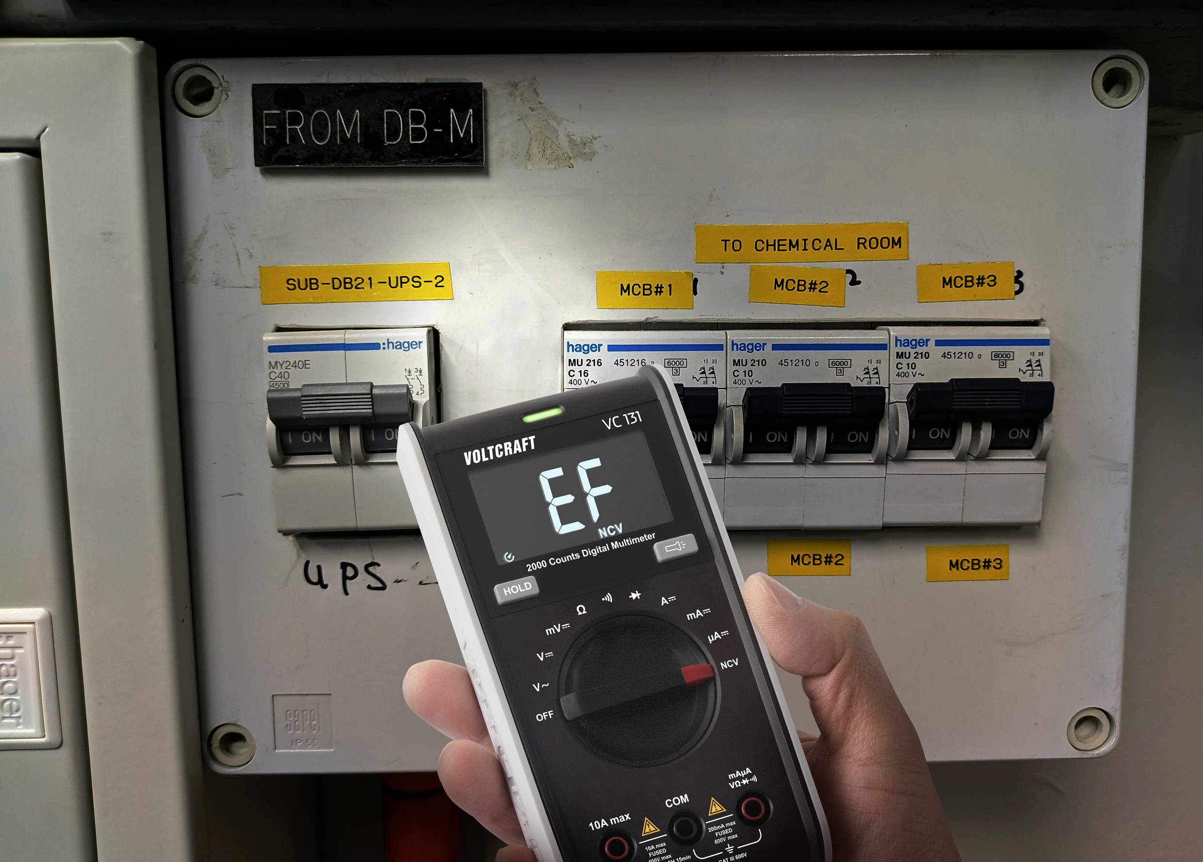 Een digitale multimeter toont 'EF' terwijl deze gericht is op een schakelkast met meerdere zekeringen. Borden geven verschillende stroomcircuits aan.