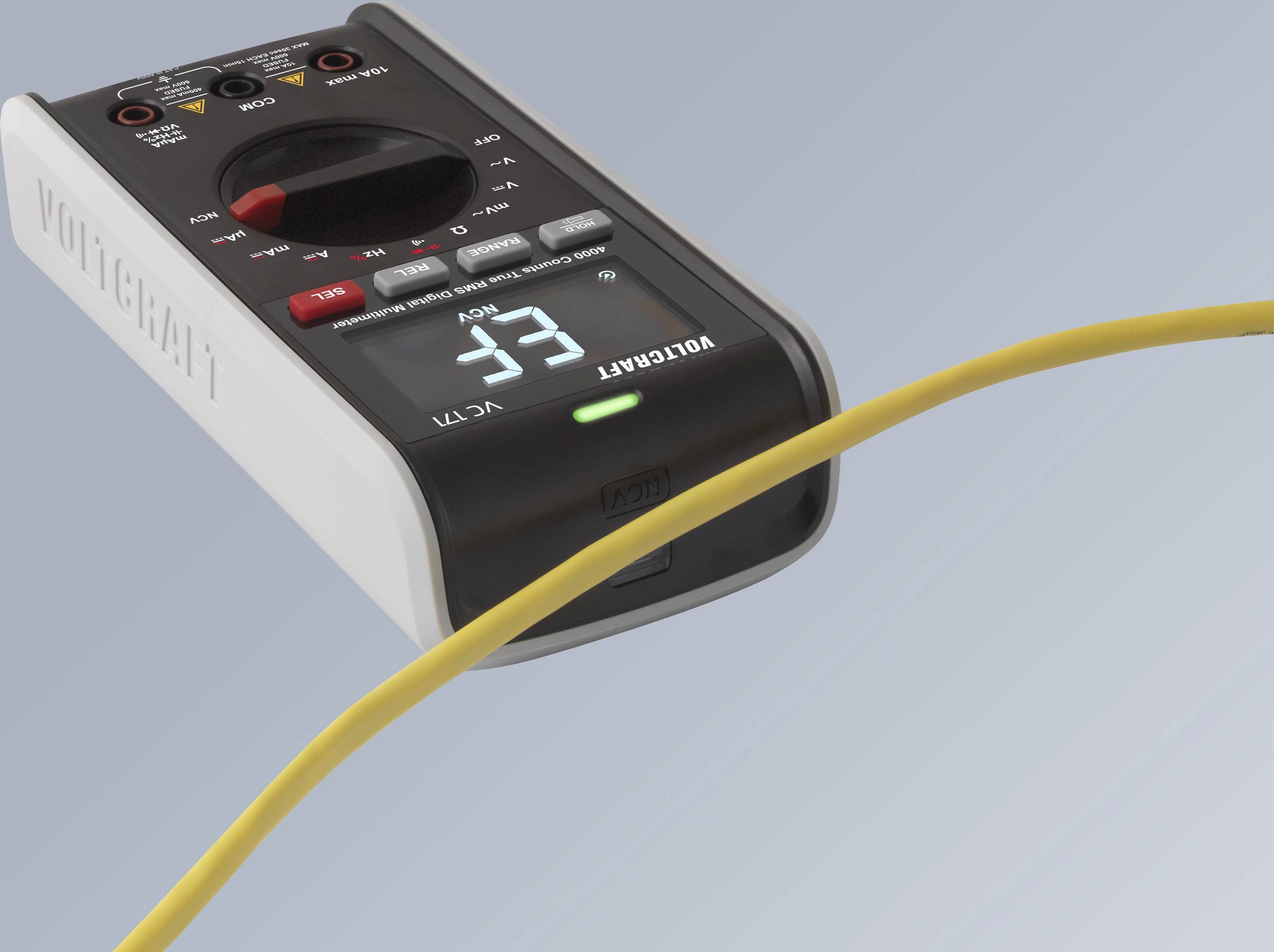 Een digitale multimeter toont een waarde van 3,3. Een geel kabel is op de voorgrond zichtbaar, terwijl het apparaat op een tafel ligt.