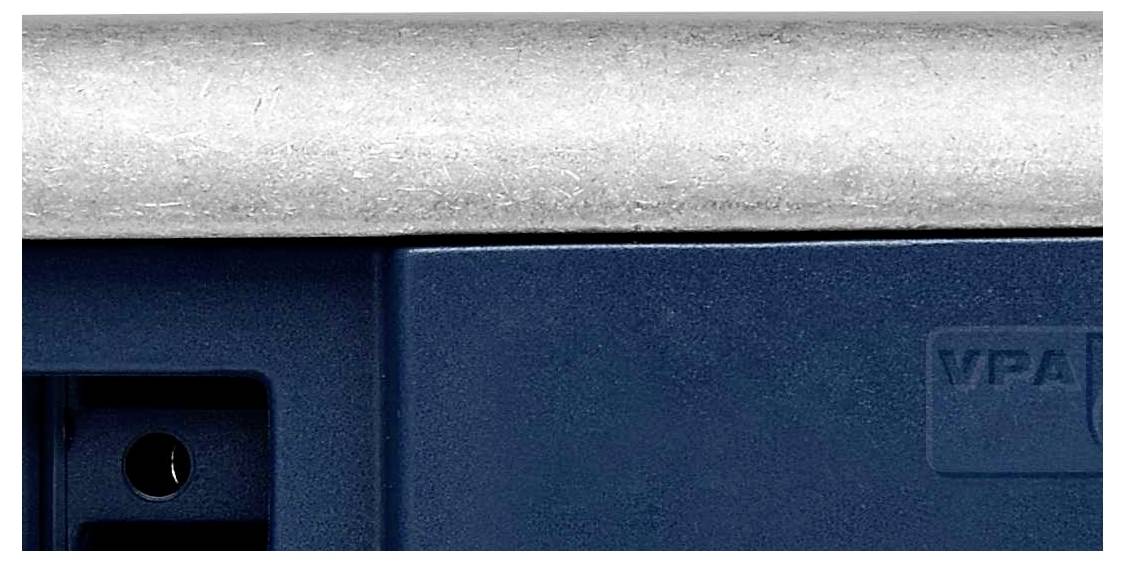 Een blauw metalen voorwerp met een grijze, gestructureerde rand bovenaan. Aan de rechterkant is een deel van een logo zichtbaar.