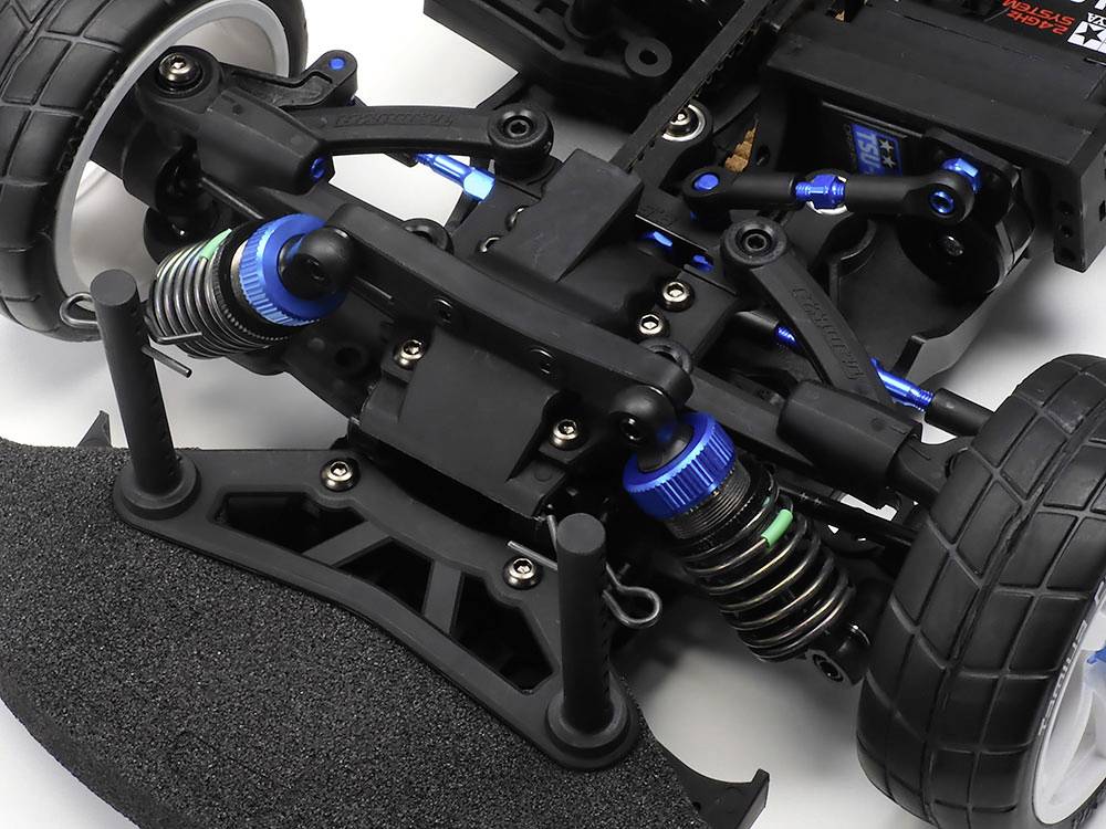 Close-up van een op afstand bestuurd autochassis van kunststof en metaal, met vering en blauwe accenten.