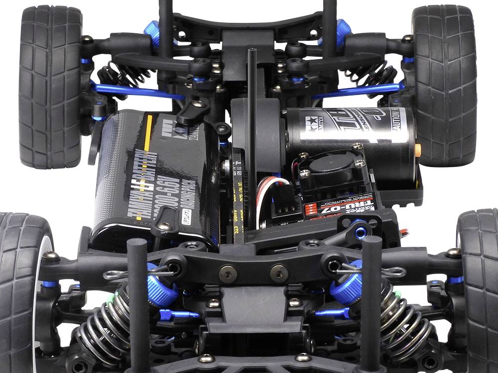 Close-up van een radiografisch bestuurbare modelauto-chassis met zichtbare motor, schokdempers en banden.