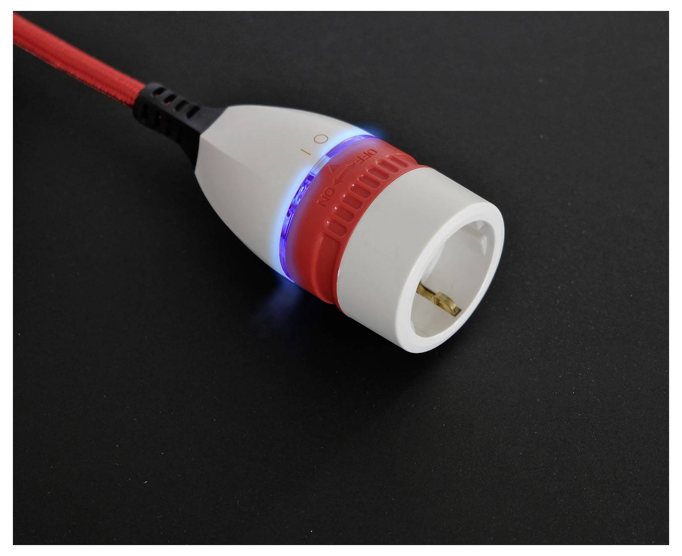 Vergroting van een rood-wit elektrische stekkeradapter met een gloeiende blauwe ring op een zwarte achtergrond.