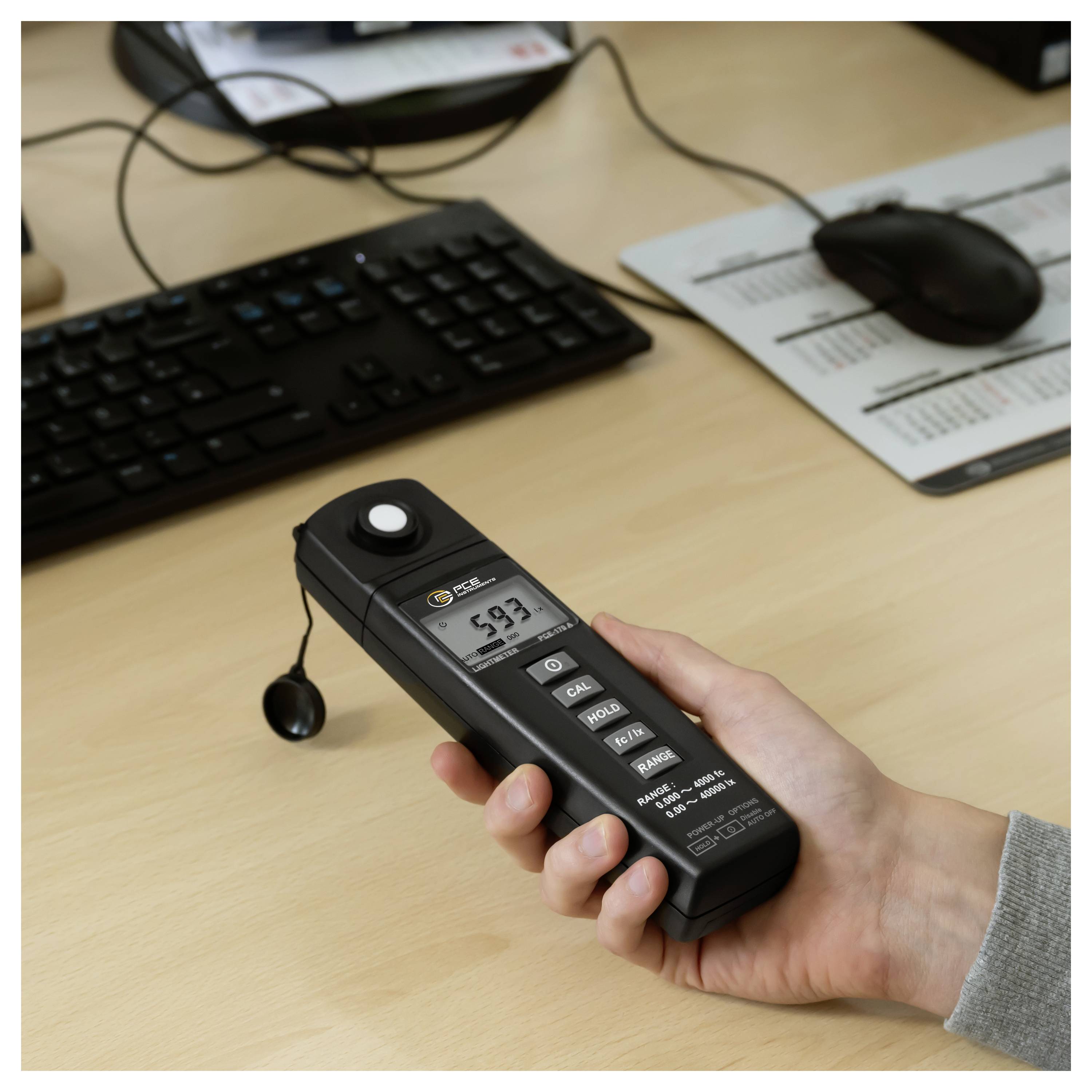 Handheld digitaal geluidspegelmeters meten 59,7 dB op een bureau in de buurt van een toetsenbord en muis in een kantooromgeving.
