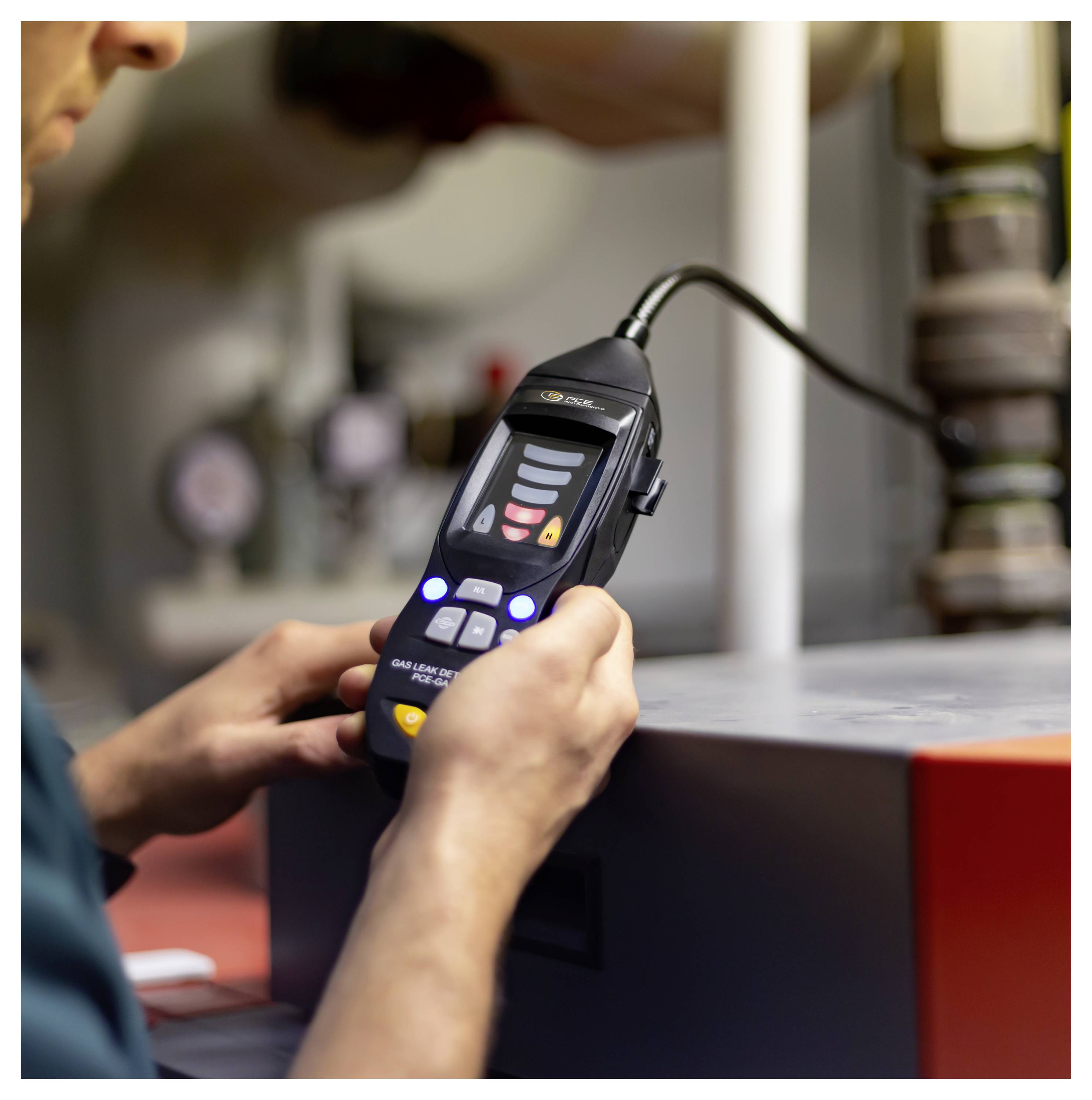 Technicus die een draagbare lekdetector met een sonde gebruikt, testapparatuur in een industriële omgeving.