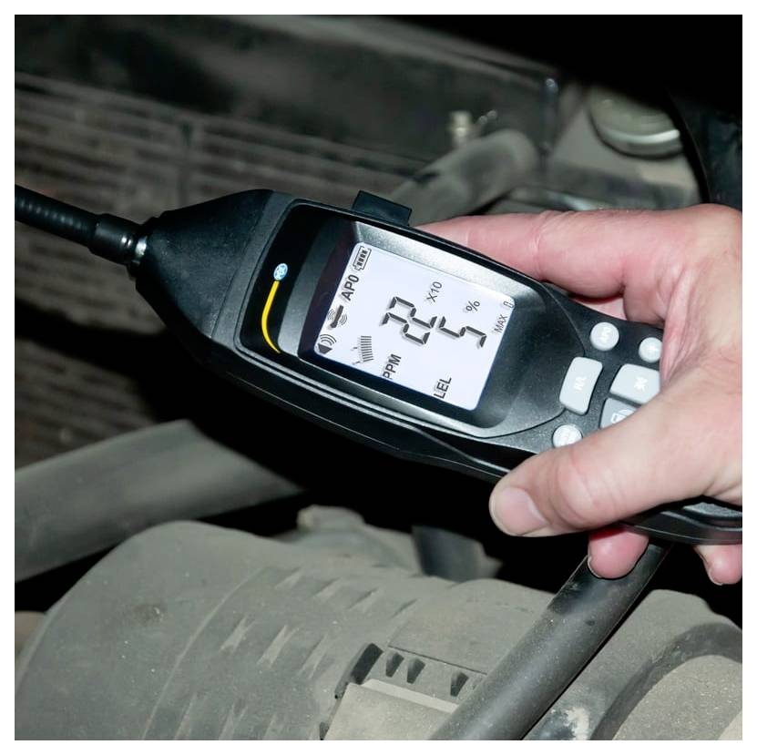 Draagbare digitale luchtkwaliteitsmeter die een PM2.5-waarde van 22 weergeeft en 5% batterij terwijl deze in de buurt van het interieur van een voertuig wordt vastgehouden.