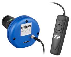 Een blauw rond apparaat aangesloten met een kabel, naast een zwarte handcontroller met een knop, waarschijnlijk voor technische instellingen.