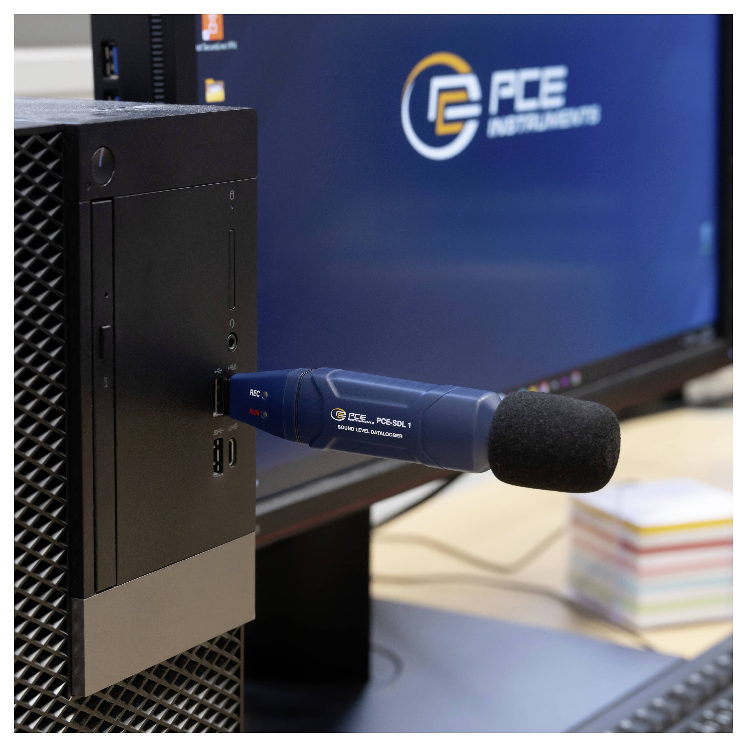 Een desktopsleutel is aangesloten op een computer naast een monitor die het logo van GFE Instruments weergeeft.