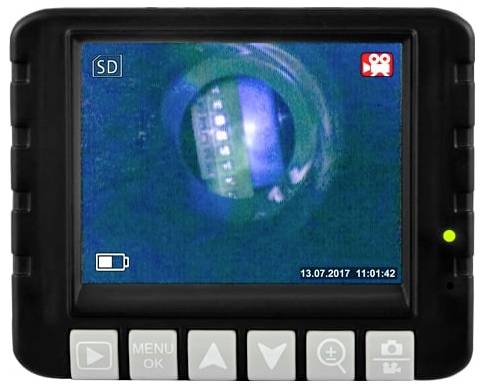 Een handheld inspectiecamera-scherm toont een close-up van het binnenwerk van een pijp of tunnel met een heldere circulaire opening en een datum-/tijdstempel op het scherm.