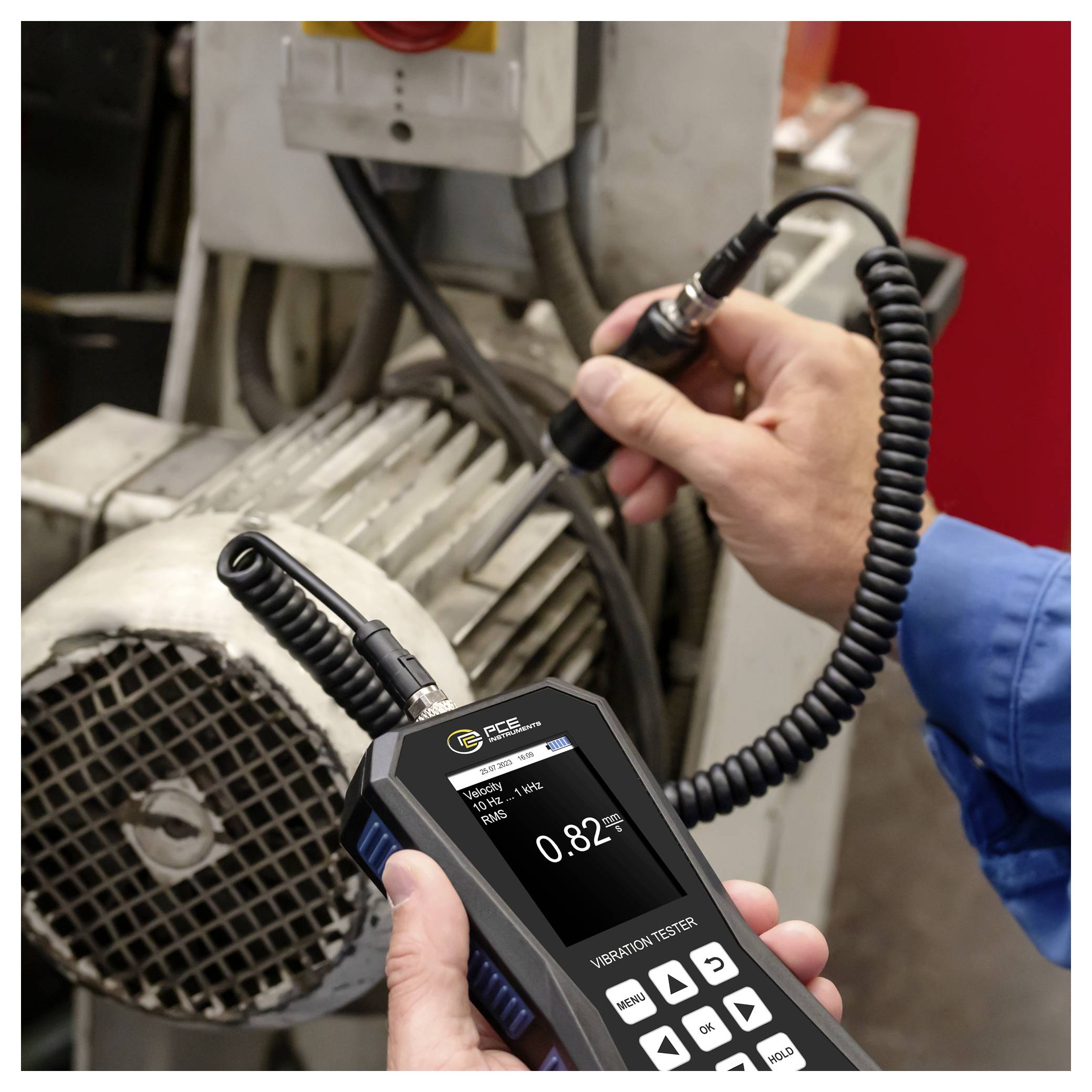 Technicus gebruikt een trillingmeter op een elektromotor, waarbij het apparaat een waarde van 0,82 weergeeft.