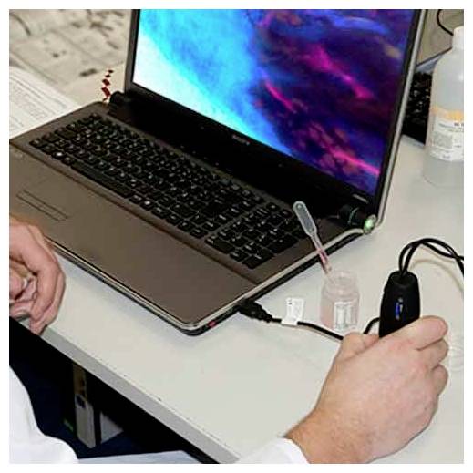 Handen op een laptop op een bureau, met een pipet en een kleine monstercontainer ernaast, wat op een lab- of testopstelling duidt.