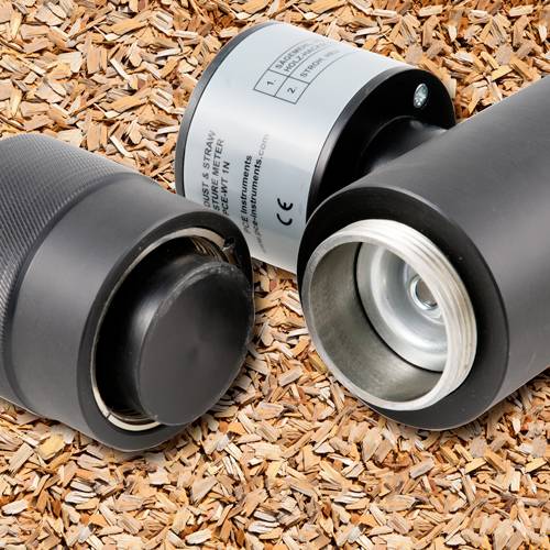 Twee zwarte metalen cilinders, waarvan één open, tonen de binnenste mechaniek, geplaatst op een achtergrond van houten houtspaanders.