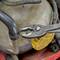 Een KNIPEX-tang houdt een rubberen slang vast, omgeven door metalen onderdelen in een werkplaatsomgeving.